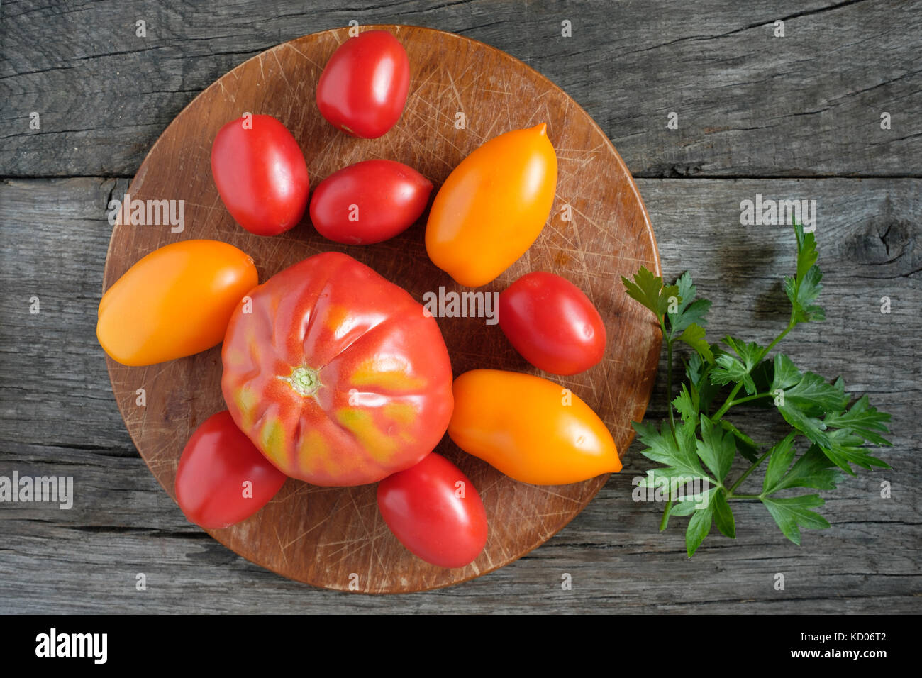 Red and yellow tomatoes with parsley on rustic wooden board Stock Photo ...