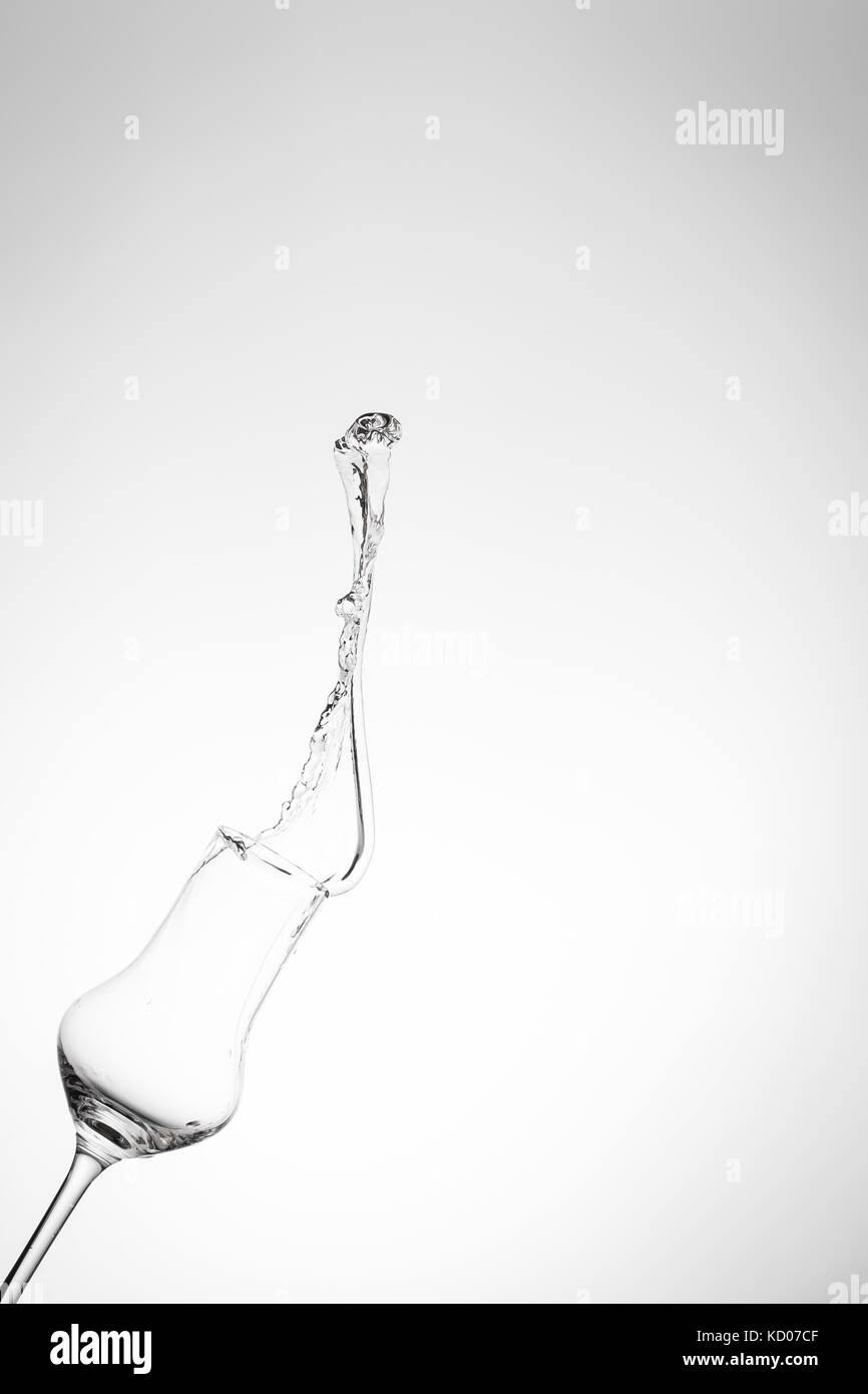 Grappa sloshing out of a glass in the height in vertical format Stock Photo