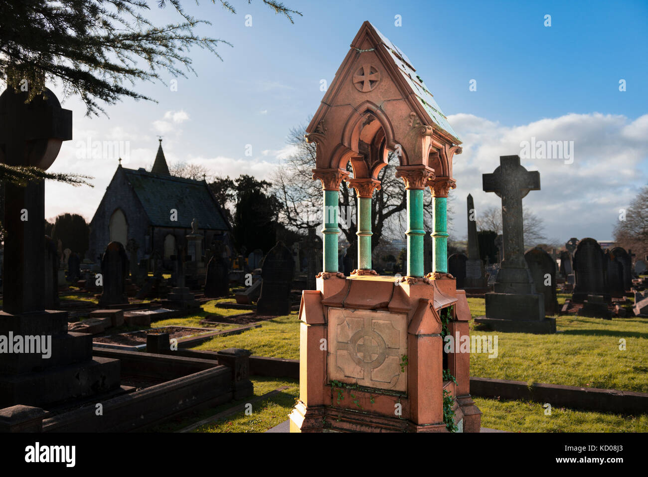Elaborate and Ornate Victorian grave monument with raised plinth, columns and pitched roof. Polished granite memorial. Sunny winter scene with chapel Stock Photo