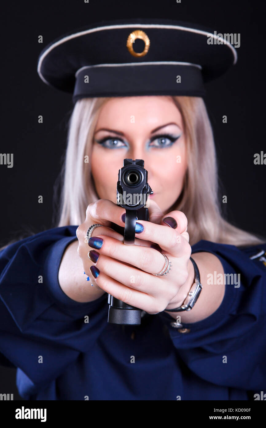 Beautiful young woman in a marine uniform with a gun over black background (focus is on the gun) Stock Photo