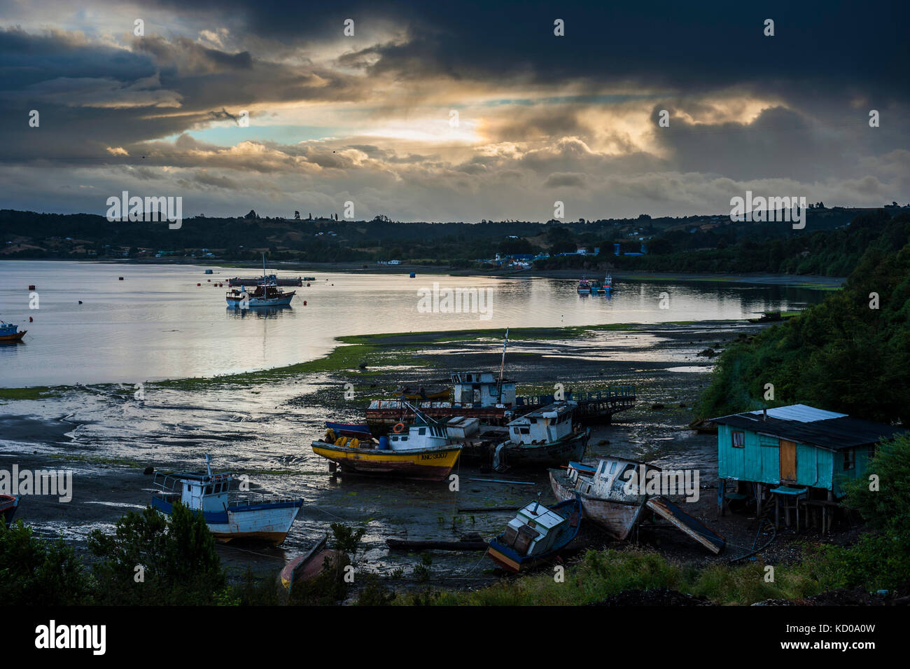 Fishing boats at low tide and sunset in Dalcahue, Chiloe, Chile Stock Photo