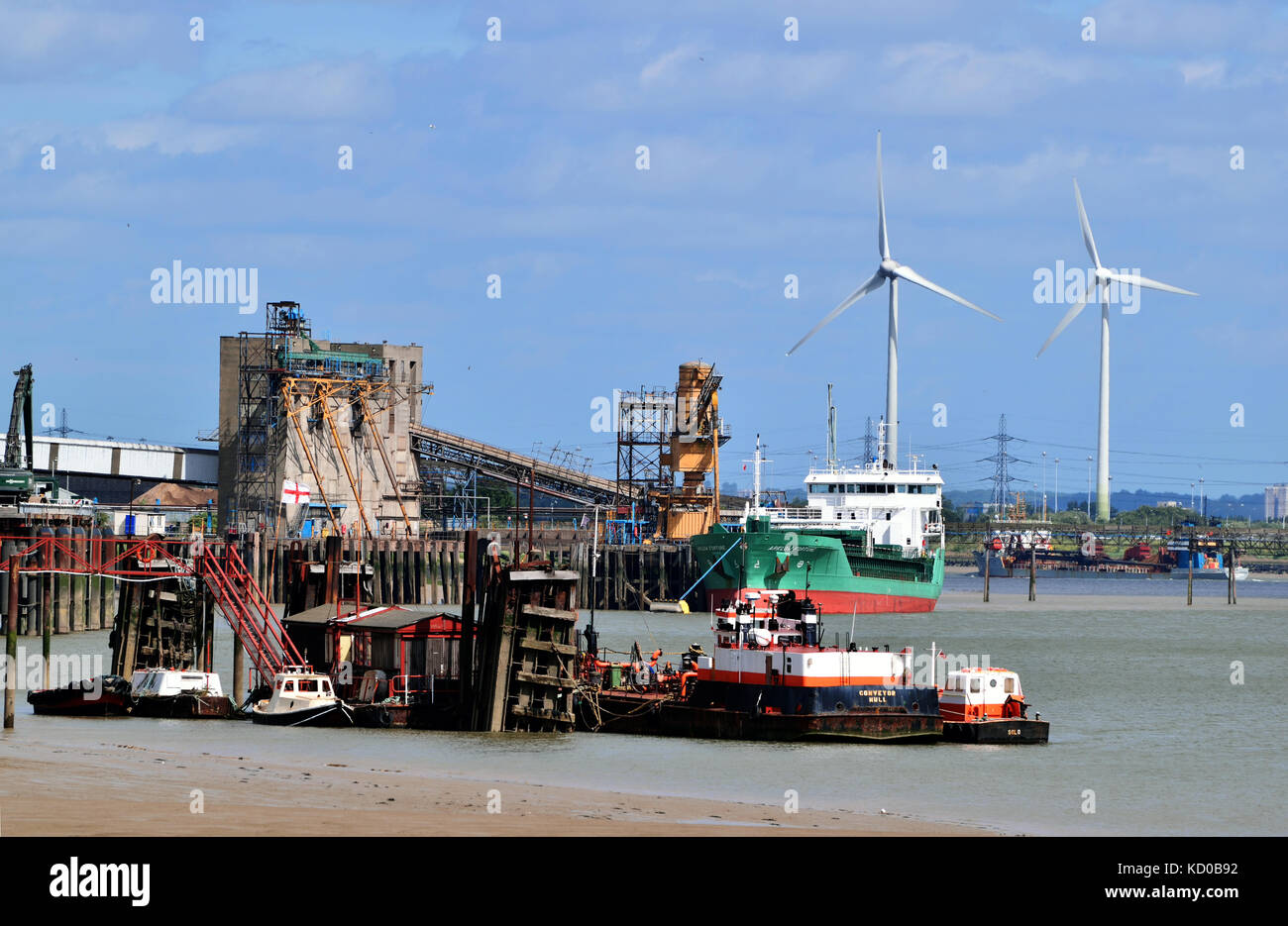 ADM Ltd oil and food processing plant adjacent to the River Thames with ship moored at dock and two wind turbines in background Stock Photo