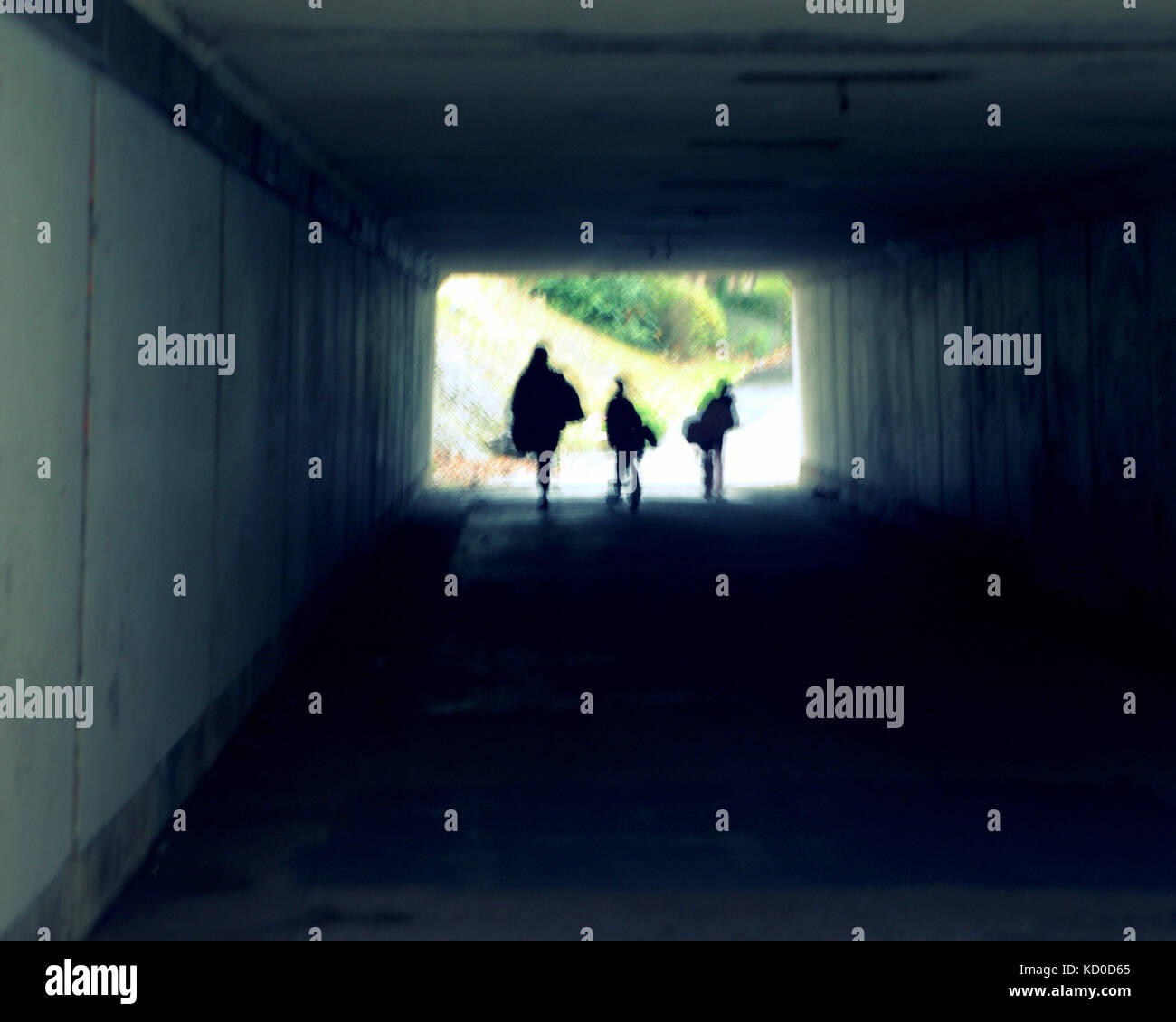 family in a tunnel underpass  heading towards light silhouette perspective mother and children Stock Photo