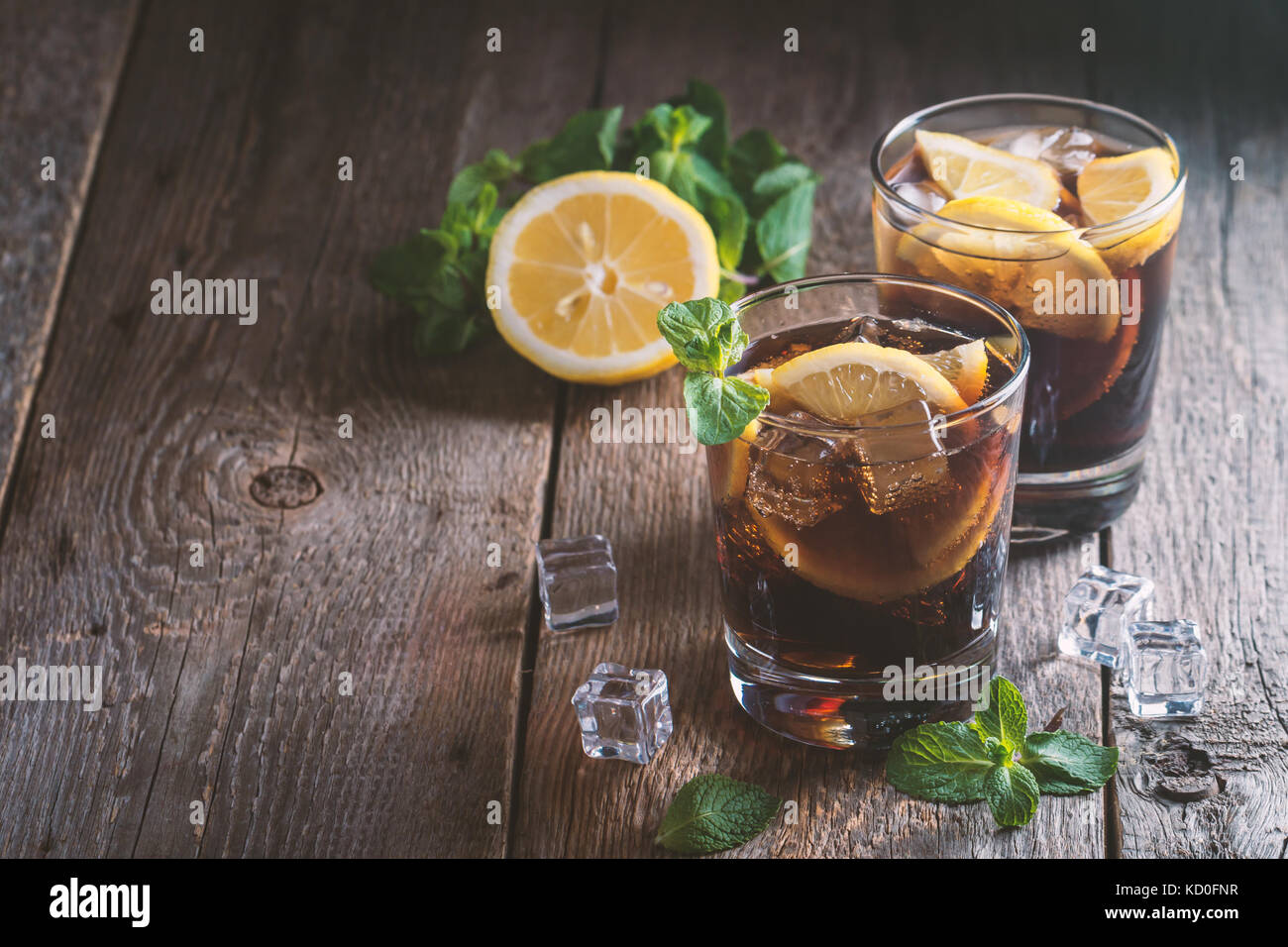 Fresh made Cuba Libre with brown rum, cola, mint and lemon on wooden