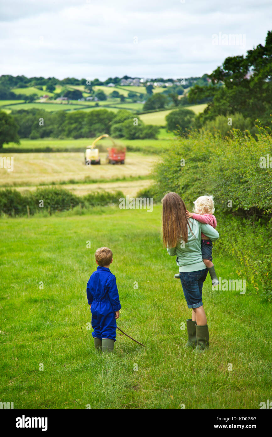 A young mother and her children watching silage making on a west country farm.UK Stock Photo