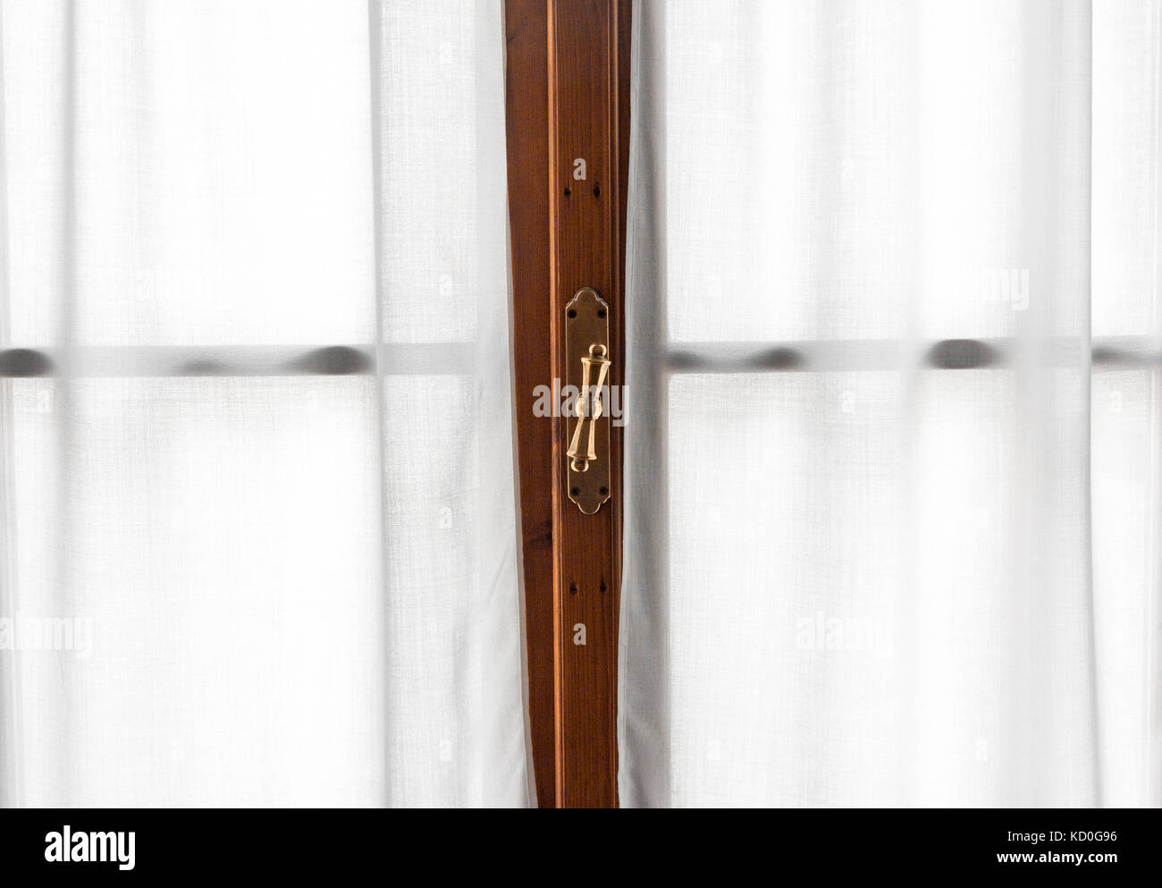 Window wooden frame detail with vintage shiny handle and white soft curtains Stock Photo