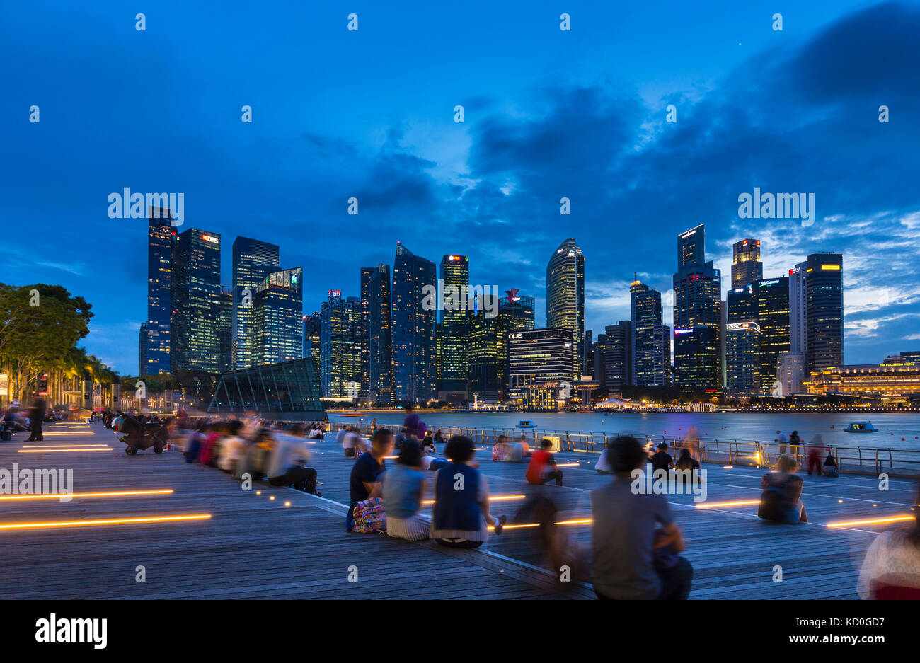 Tourists looking at city skyline from waterfront at dusk, Singapore, South East Asia Stock Photo
