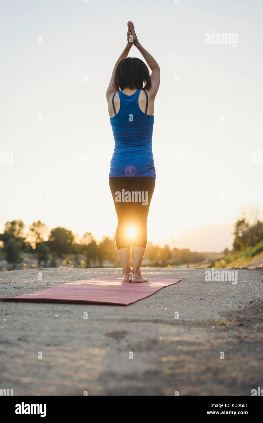 Mature woman outdoors, standing in yoga position, rear view Stock Photo ...
