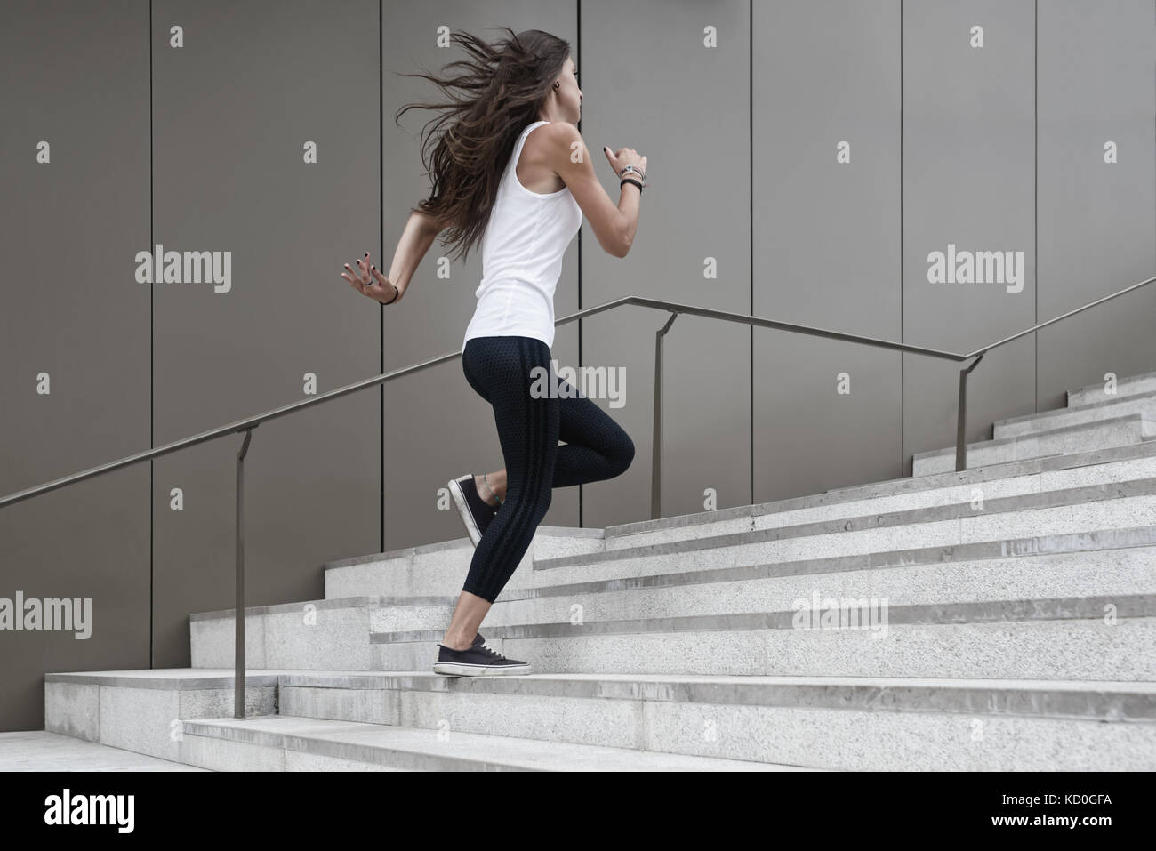 Young woman running up steps, low angle view Stock Photo