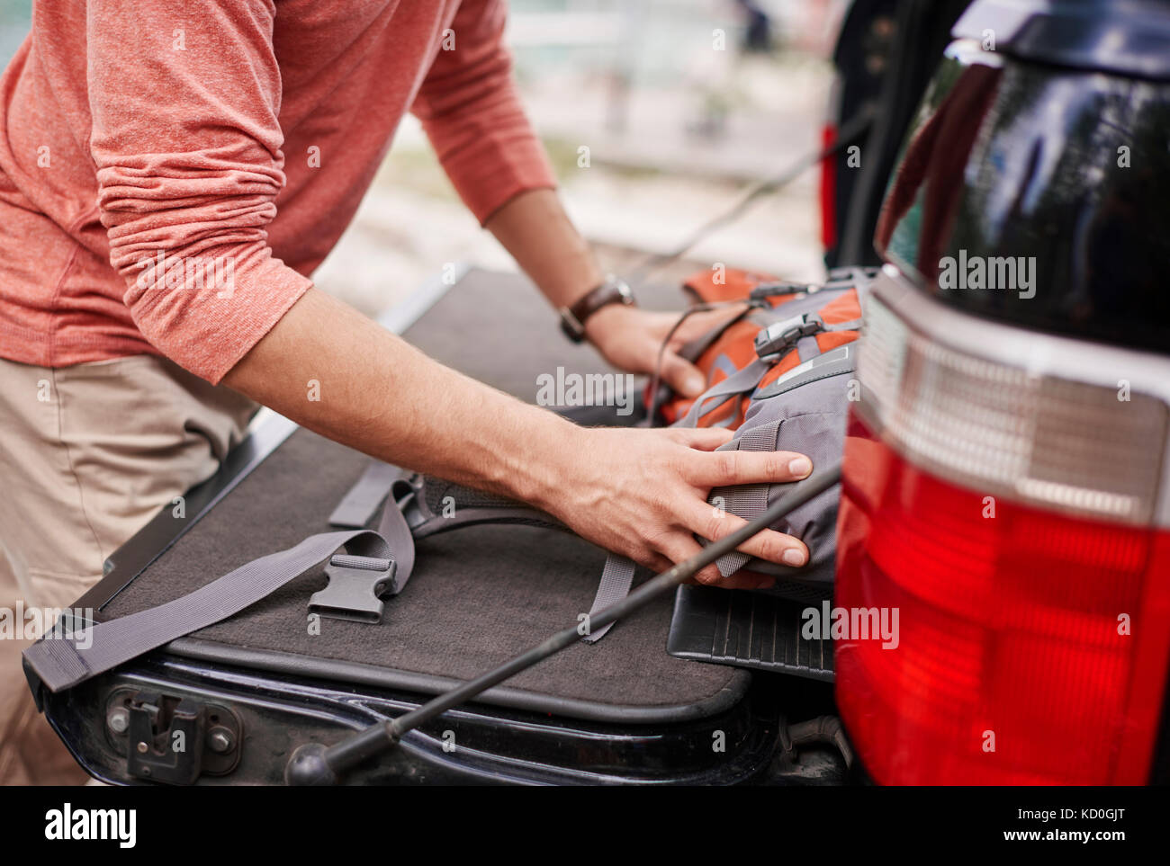 Cropped view of man putting rucksack in car boot, Krakow, Malopolskie, Poland, Europe Stock Photo