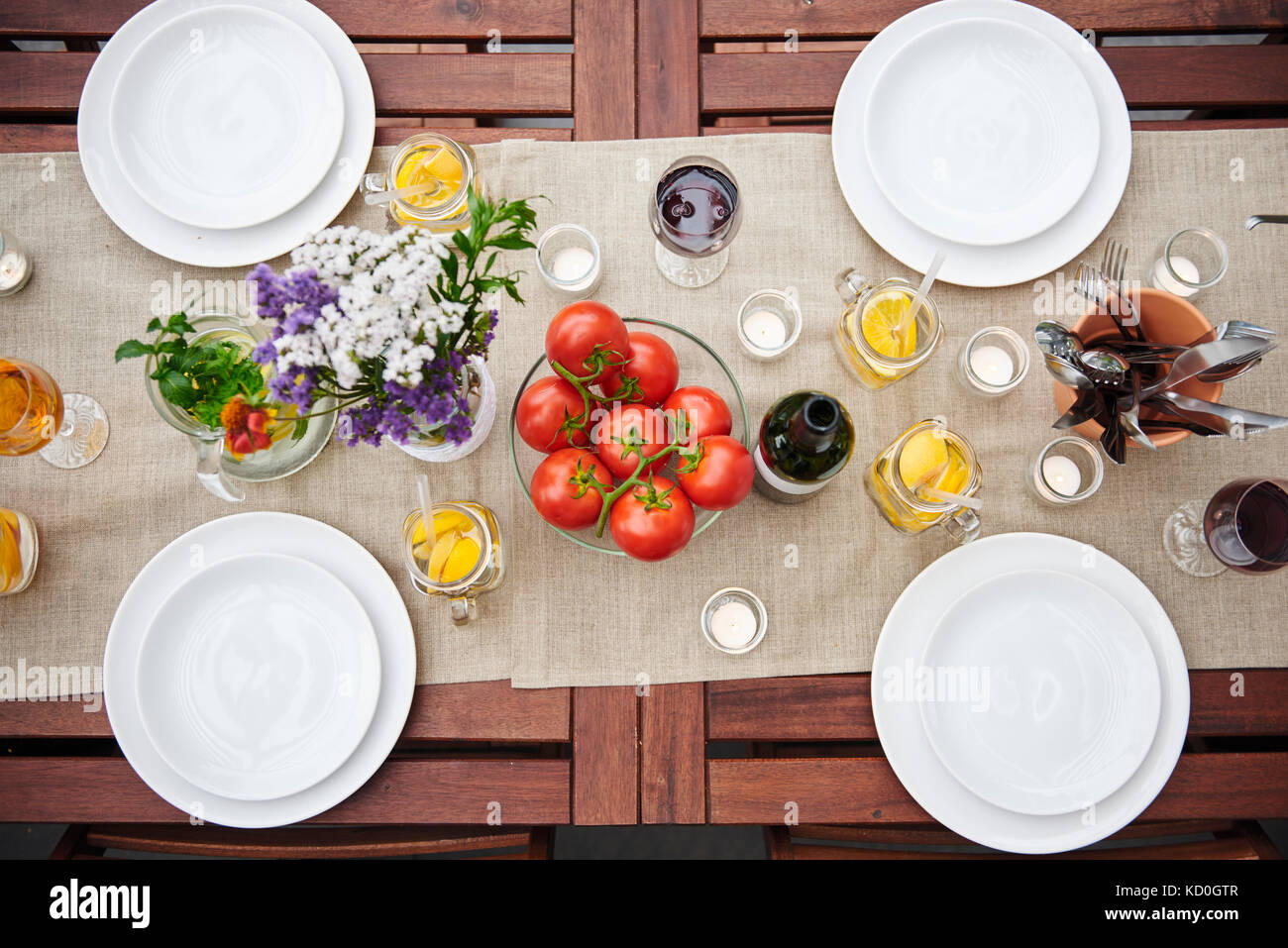 Overhead view of table prepared with flowers and vine tomatoes for