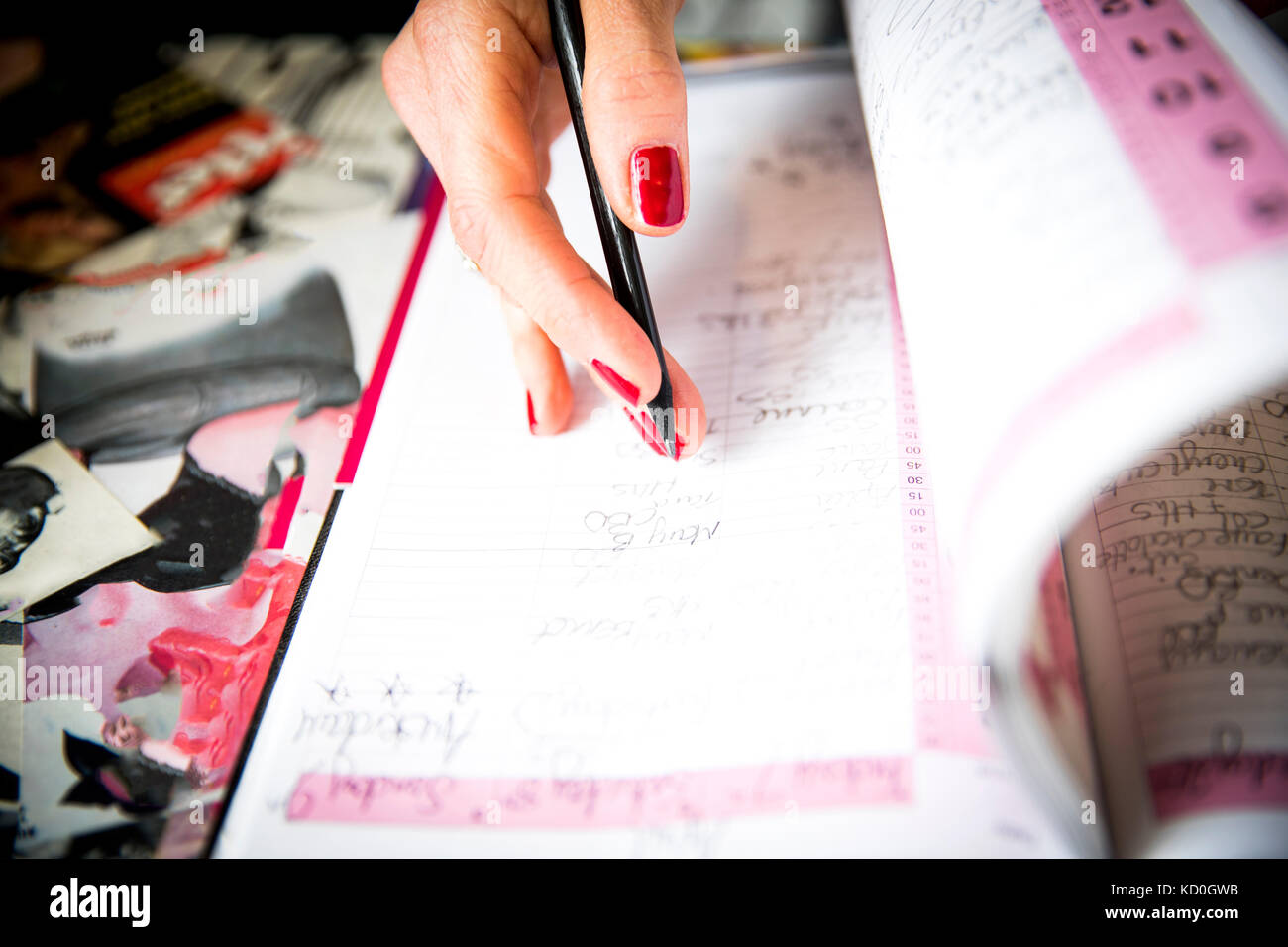 Woman writing in appointments book Stock Photo
