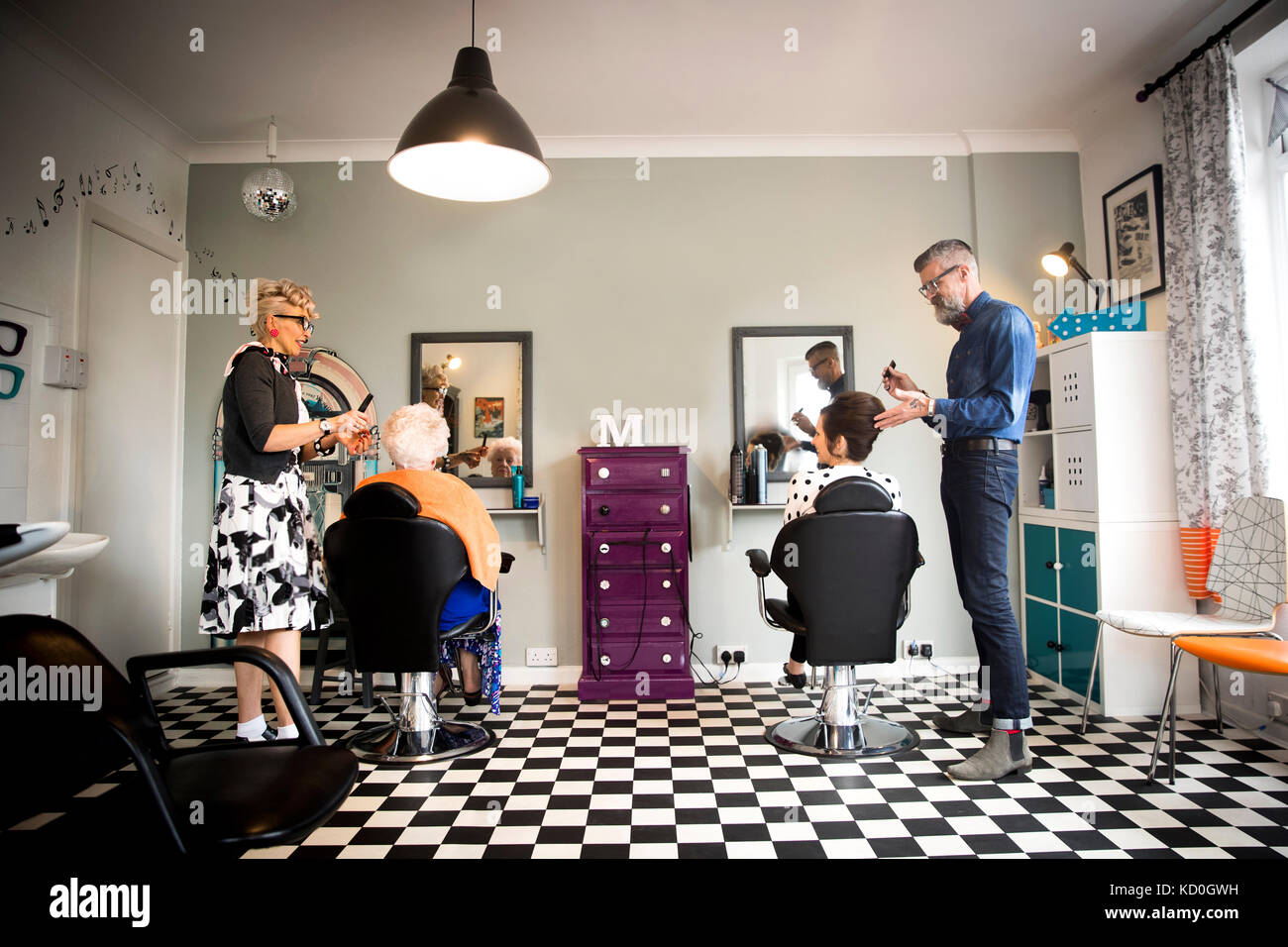 Couple in vintage clothes working on customers in quirky hair salon Stock Photo