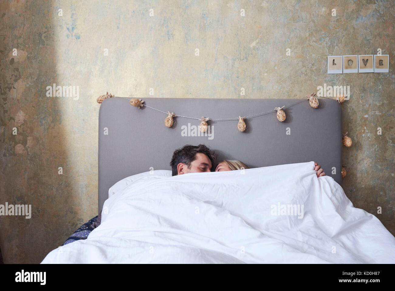 Couple in bed, under the covers, kissing Stock Photo