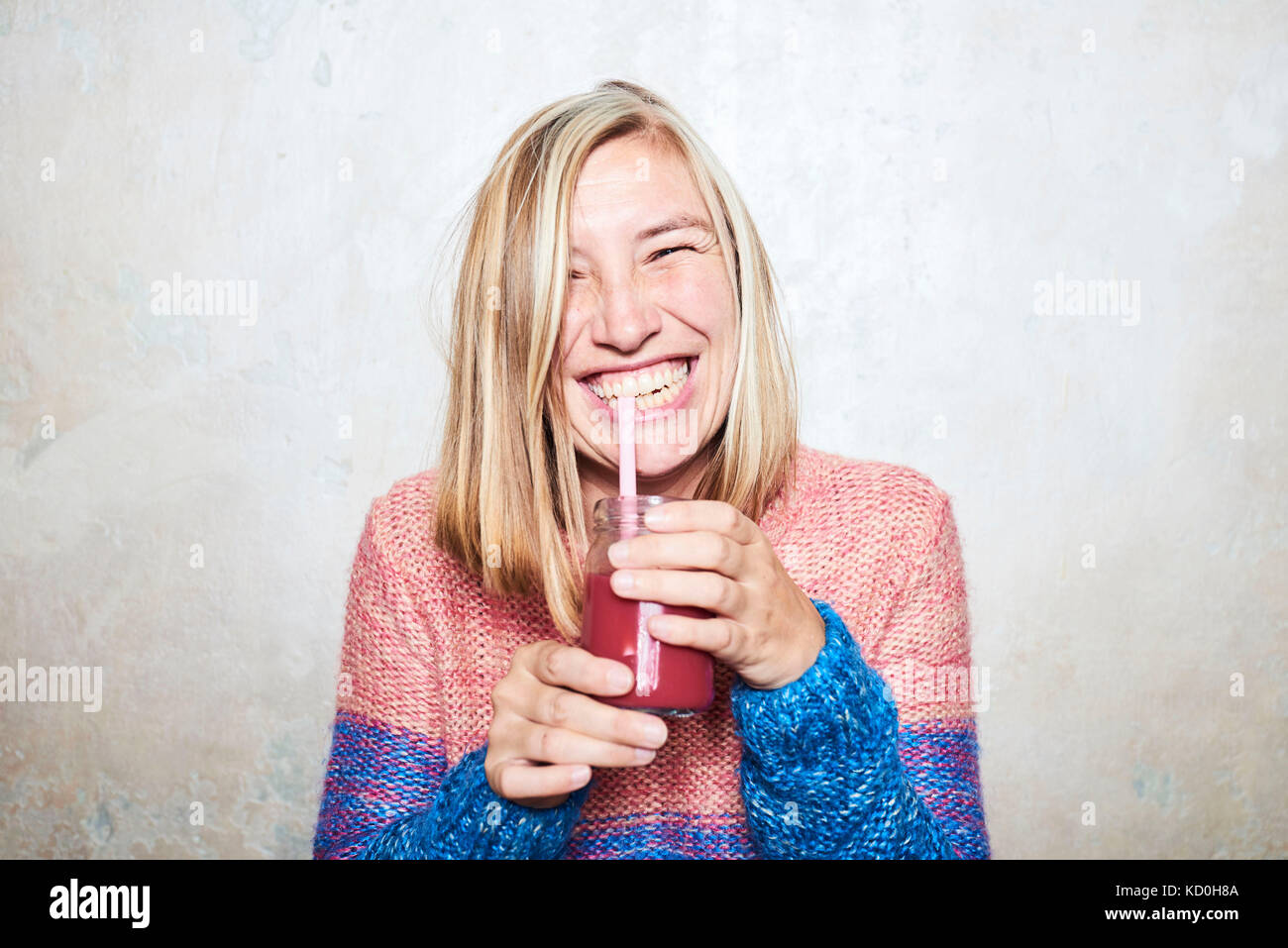 Portrait of woman drinking smoothie, smiling Stock Photo