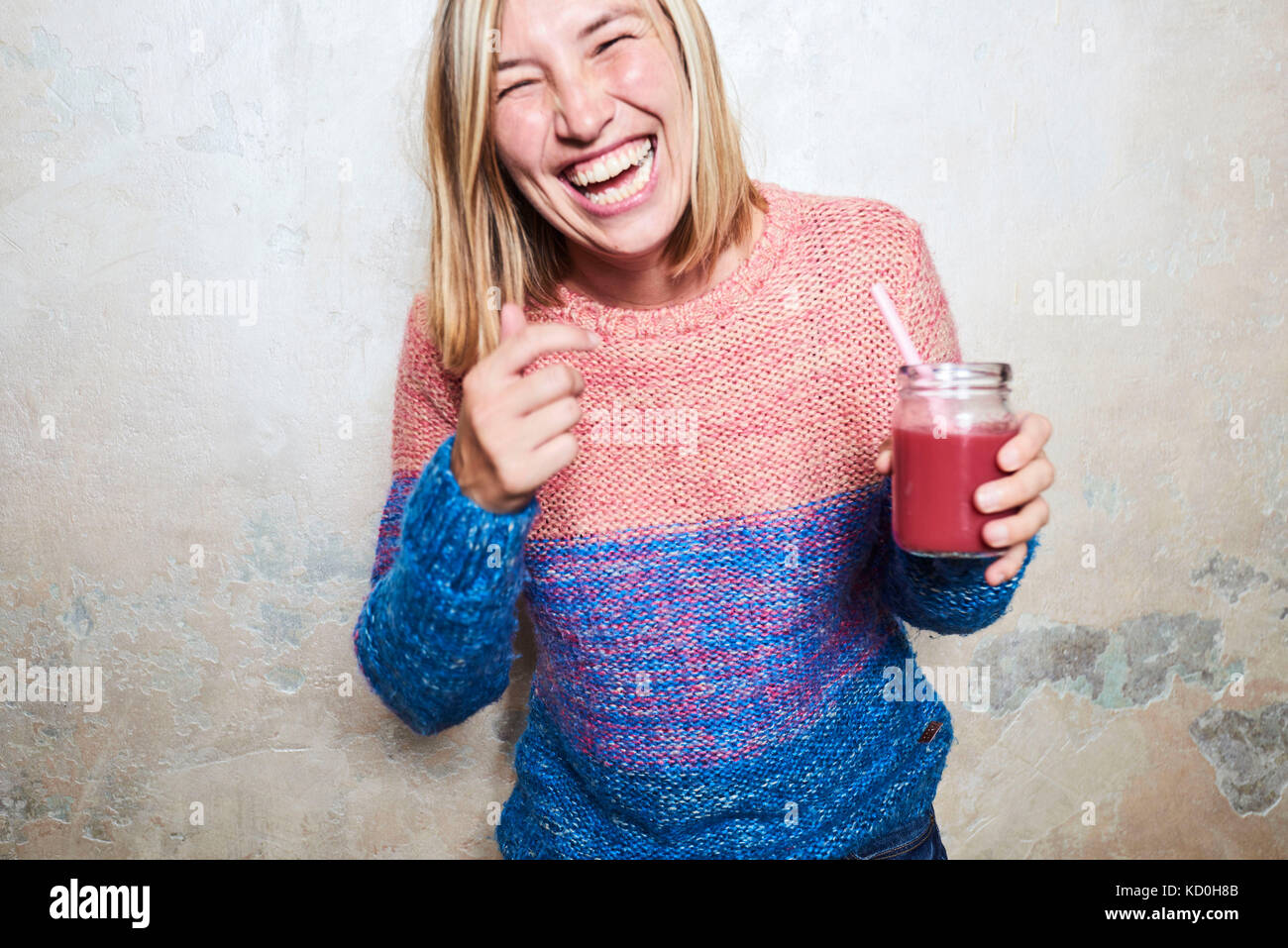 Portrait of woman holding smoothie, laughing Stock Photo
