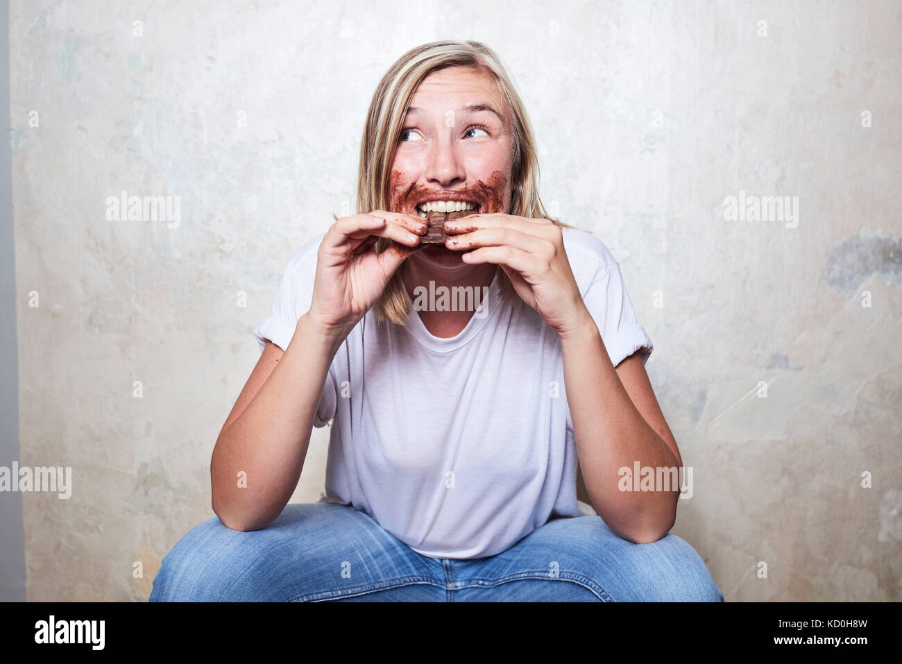 Portrait of woman eating bar of chocolate, chocolate around mouth Stock Photo