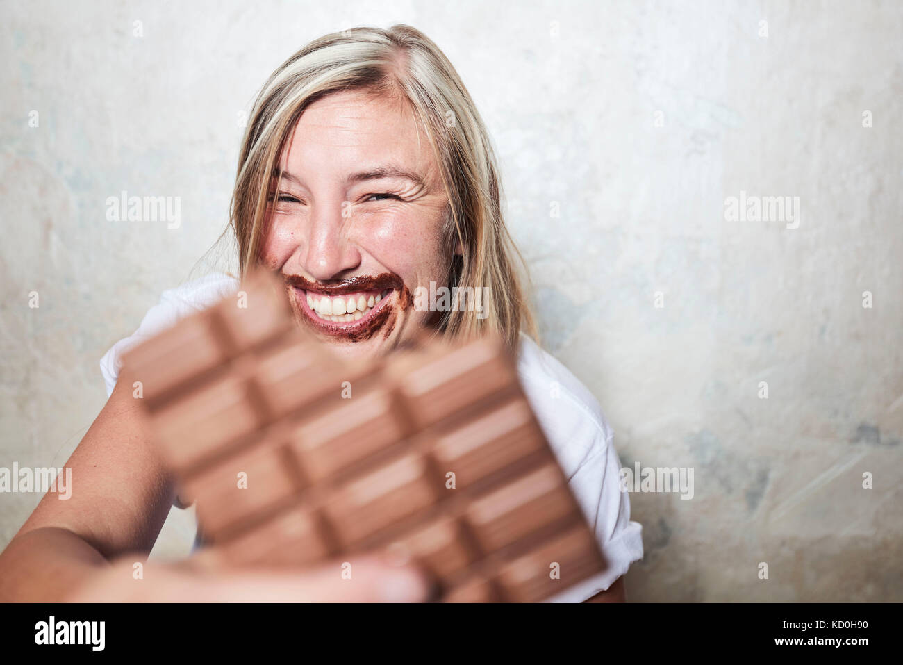 Portrait of woman eating bar of chocolate, chocolate around mouth Stock Photo