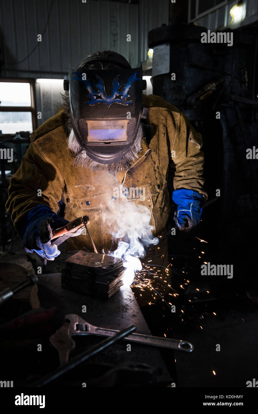 Blacksmith in welding mask welding metal in Stock Photo Alamy