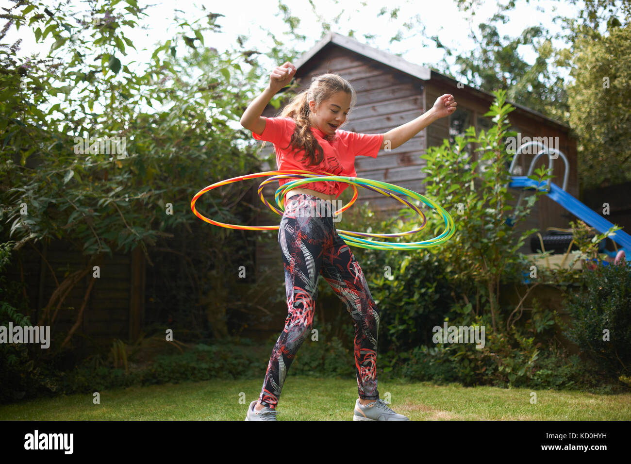 Teenage girl hula hooping with four plastic hoops in garden Stock Photo