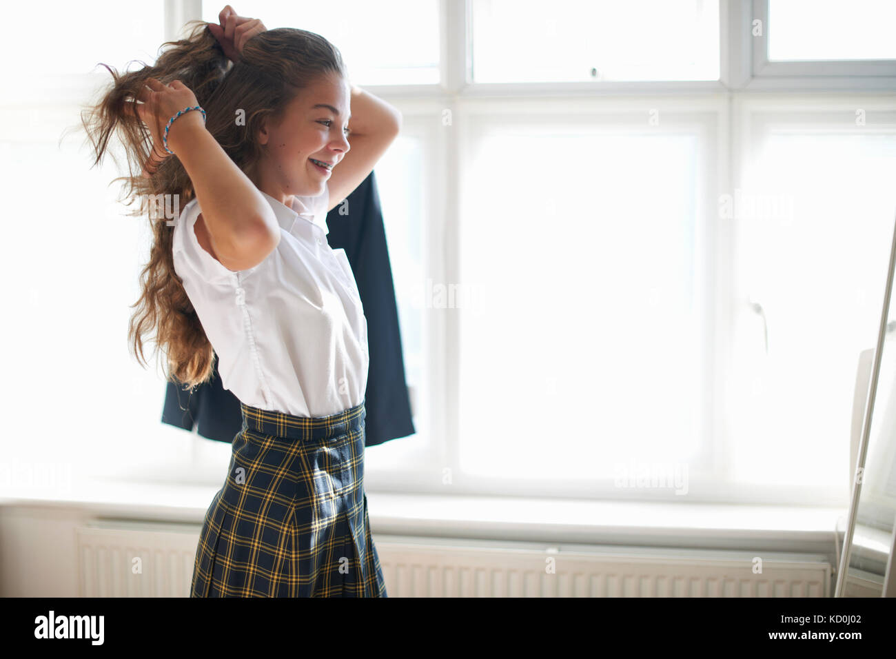 Teenage schoolgirl styling long hair in bedroom Stock Photo