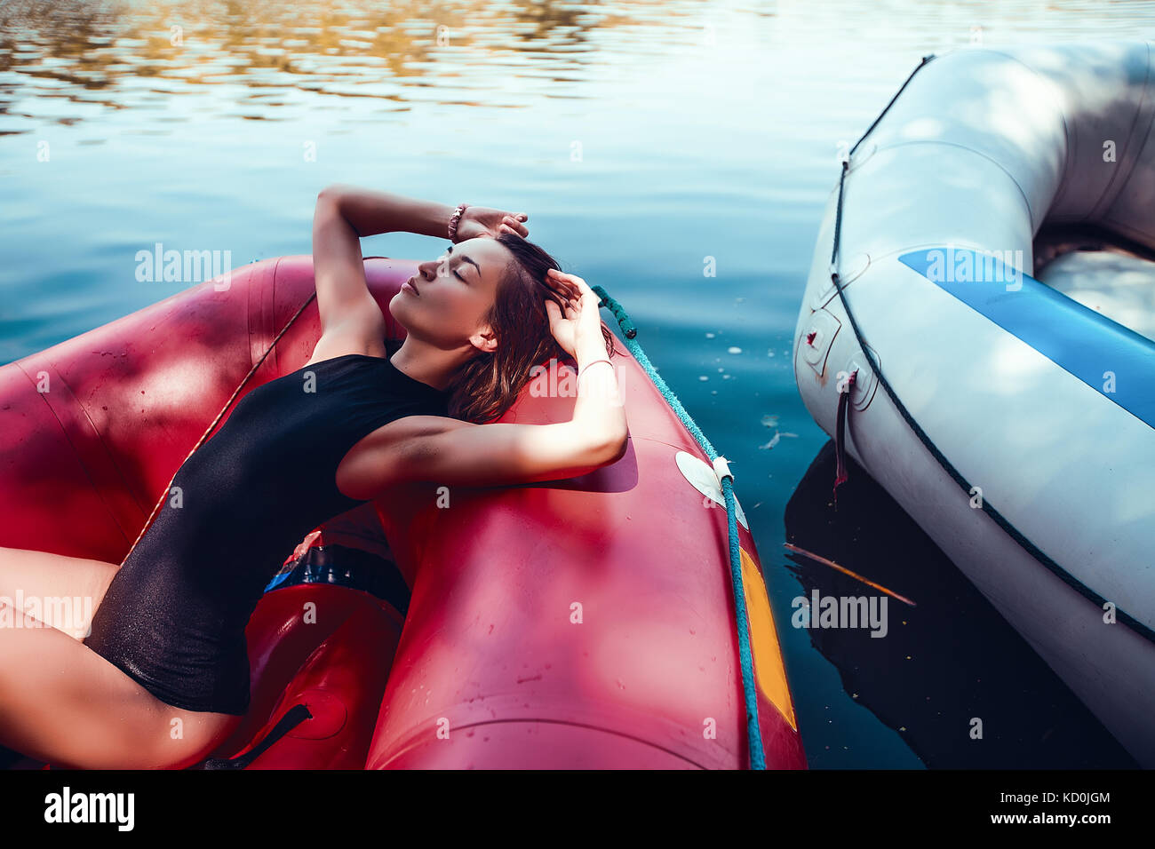 Woman wearing swimsuit lying in boat looking away Stock Photo