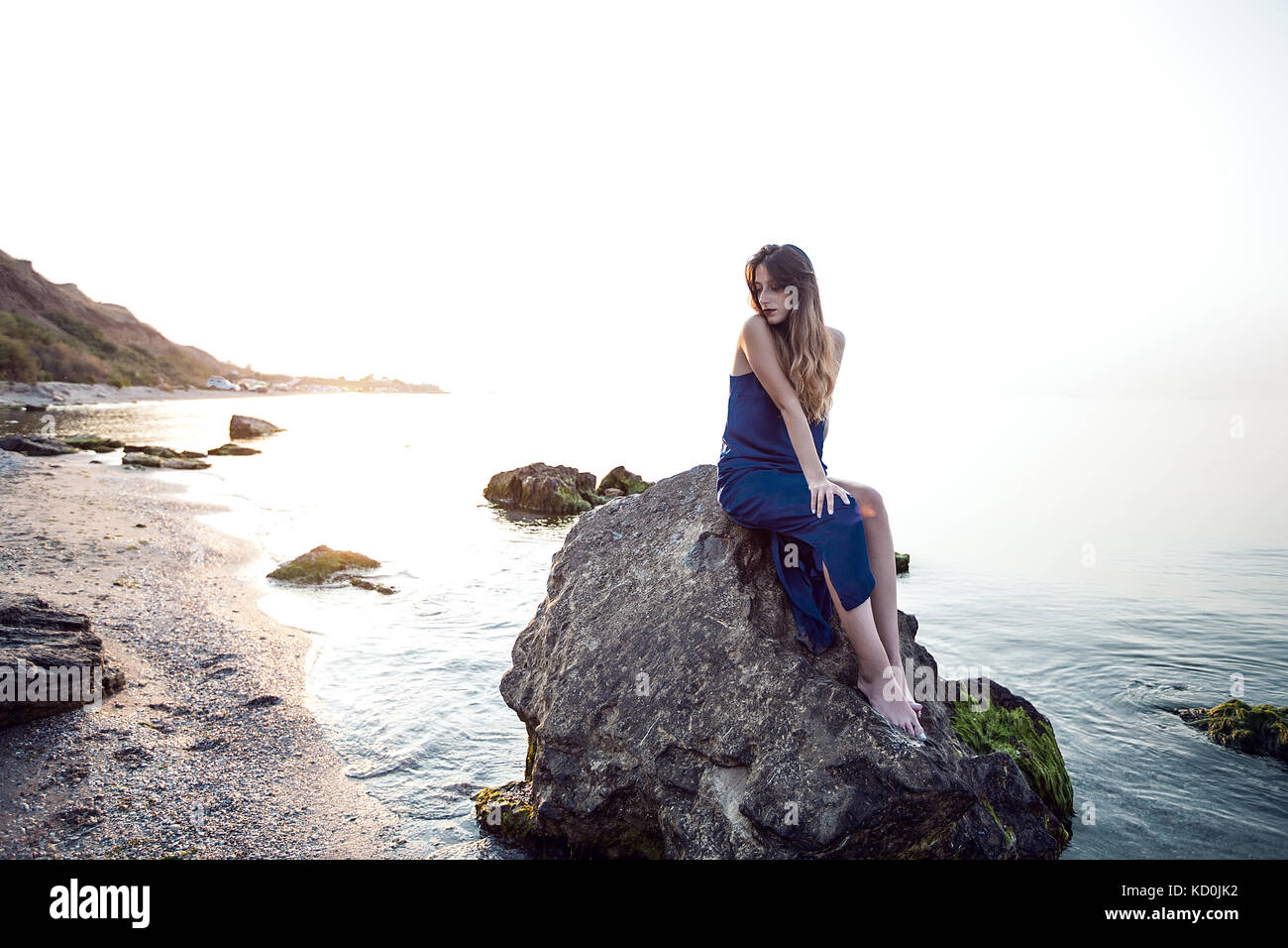 Young woman sitting on beach rock, Odessa, Ukraine Stock Photo