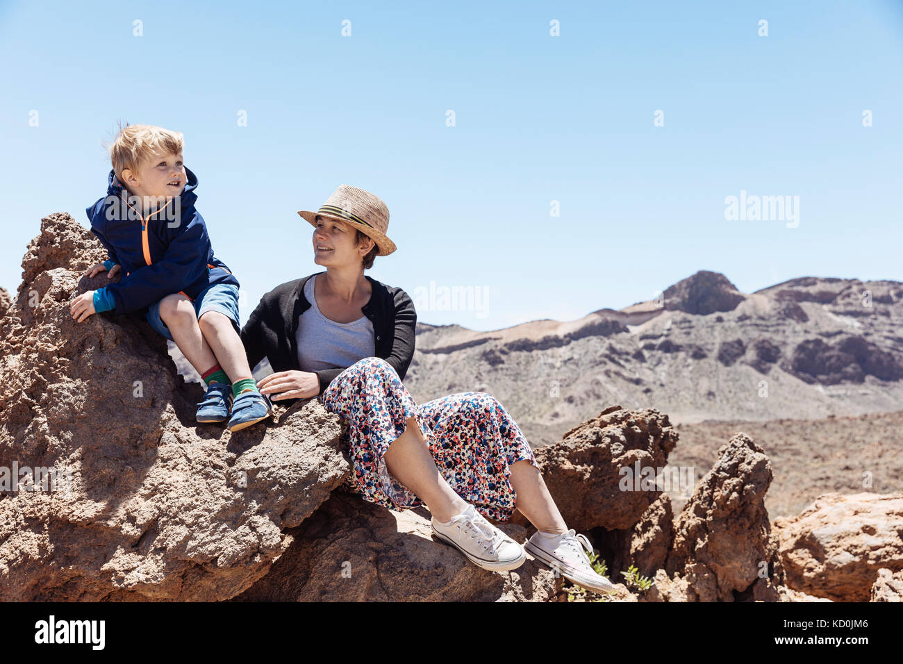 Boy and mother sitting on rocks at Mount Teide, Tenerife, Canary Islands Stock Photo