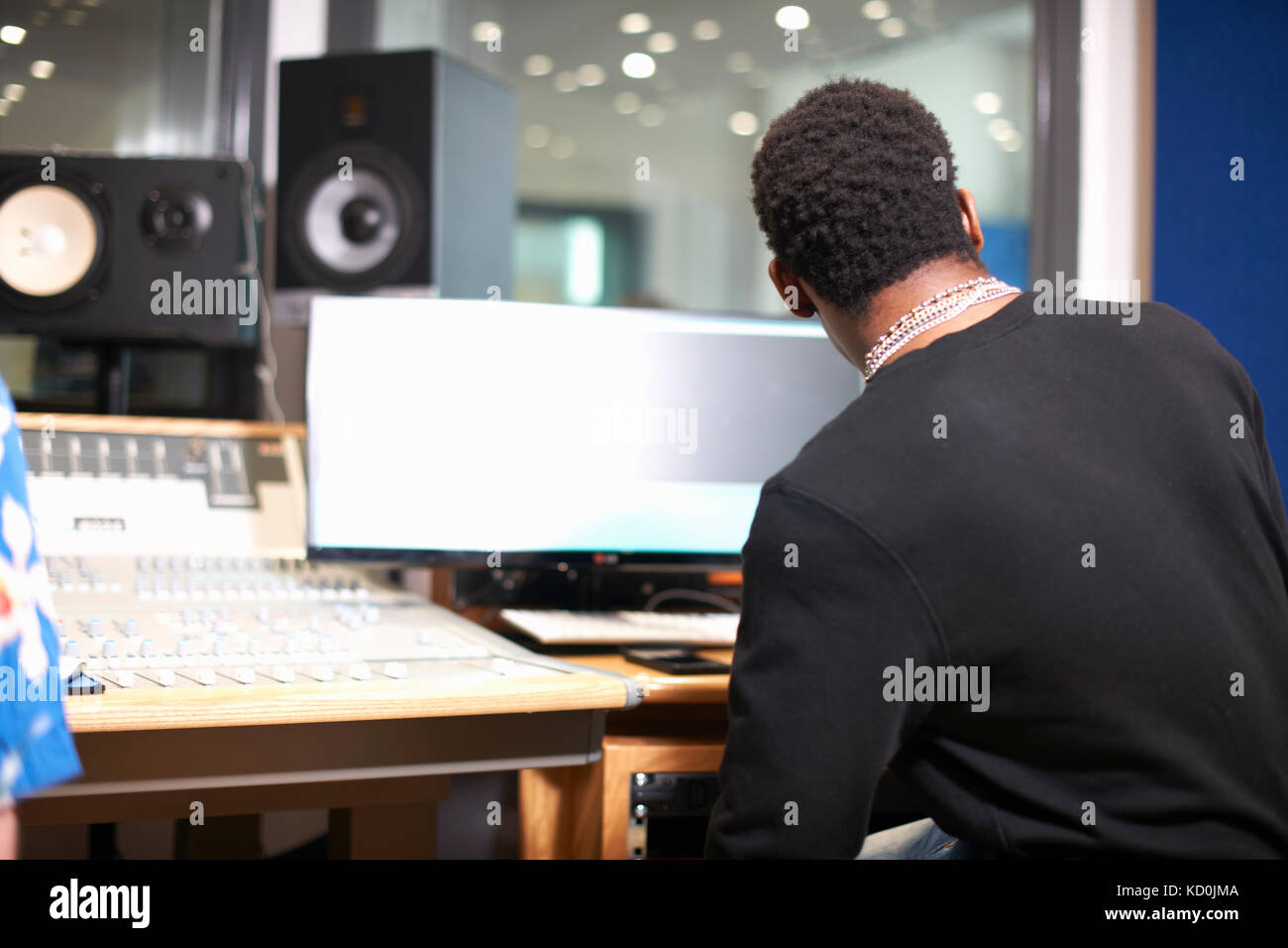Rear view of young male college student at sound mixer in recording ...