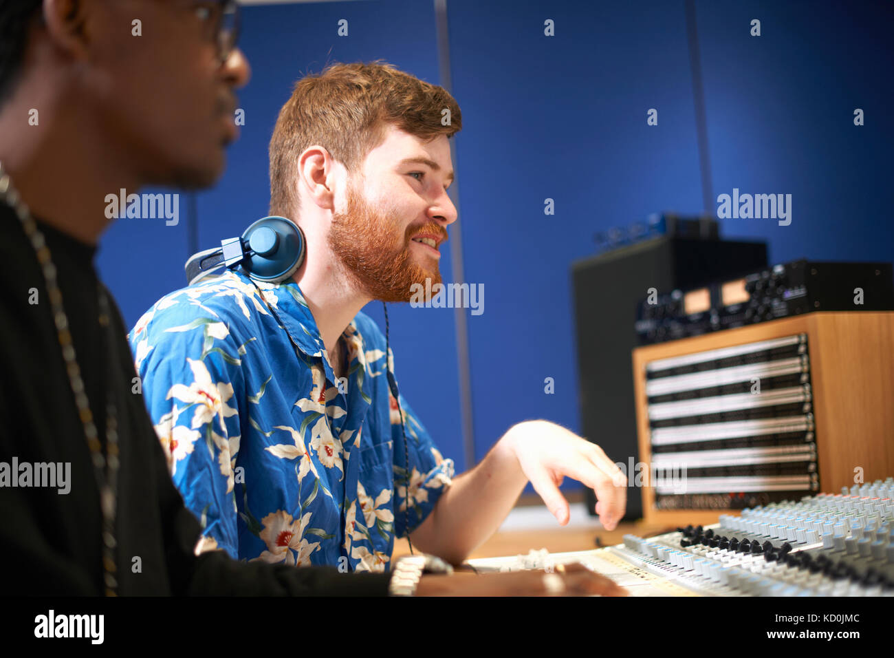 Two young male college students at sound mixer in recording studio ...