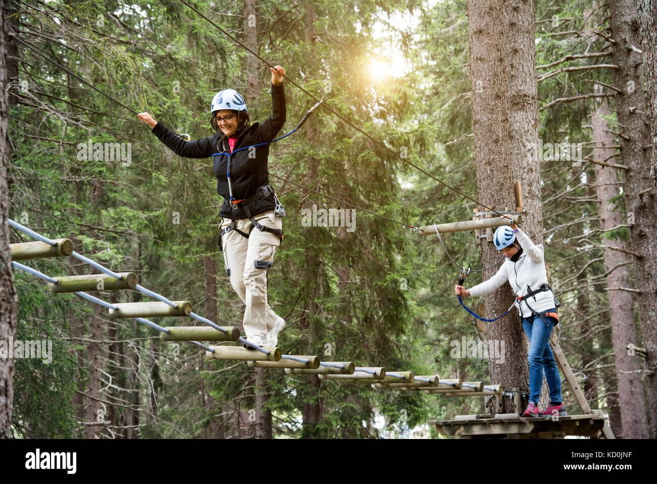 Friends in forest using high rope course Stock Photo