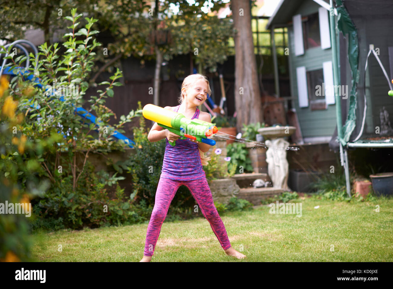 Girl squirting water gun in garden Stock Photo