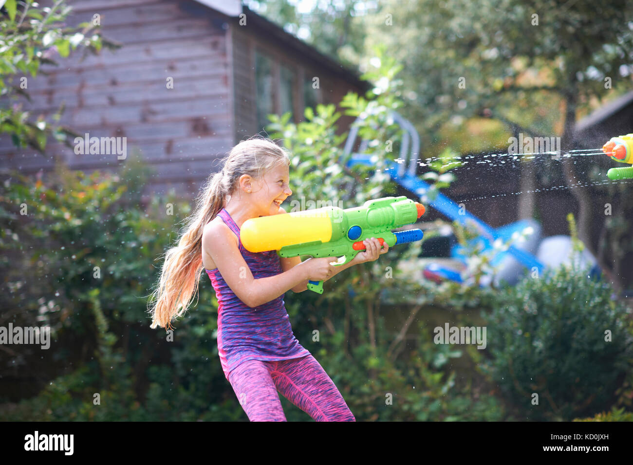 Girl squirting water gun in garden Stock Photo
