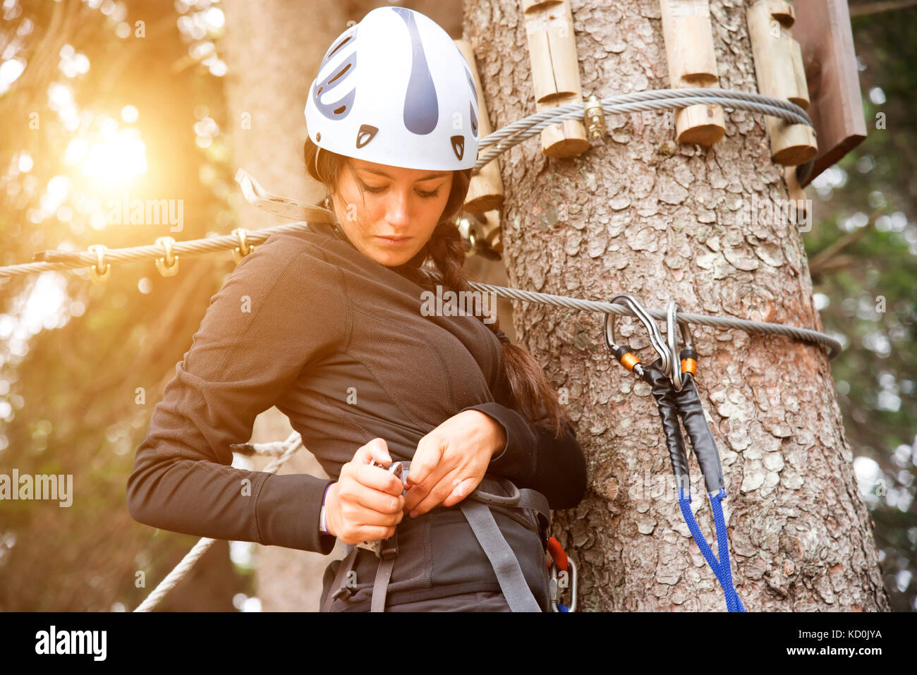 Teenage girl up tree preparing to use high rope course Stock Photo