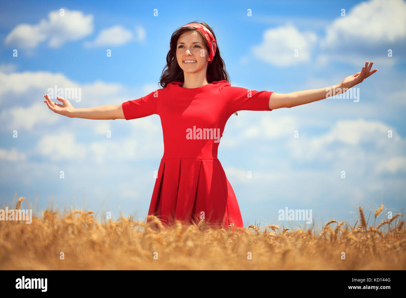Young woman with hands raised up in the wheat field over blue sky in ...