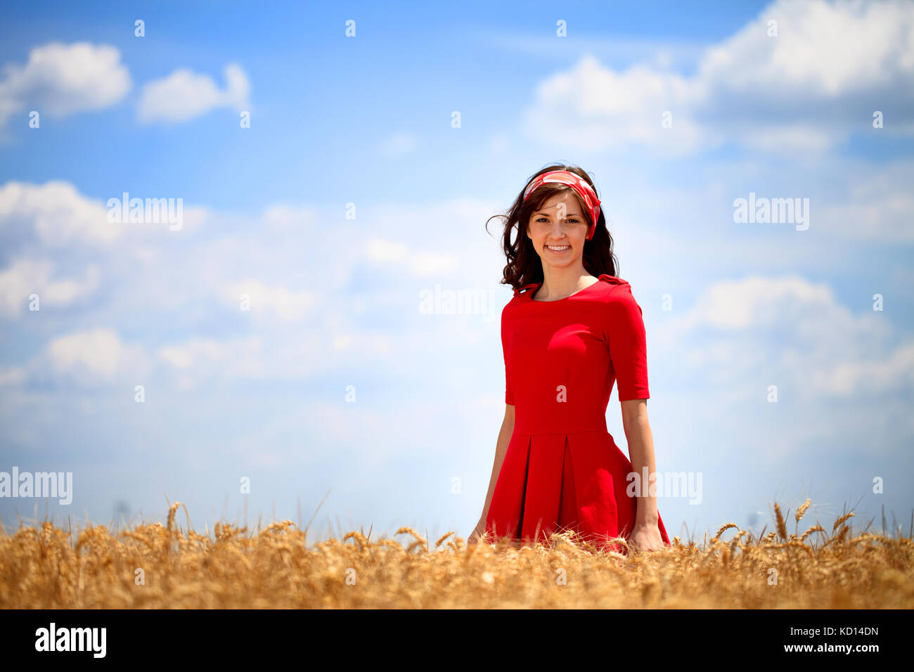 Young lovely girl in red dress standing in golden field Stock Photo - Alamy