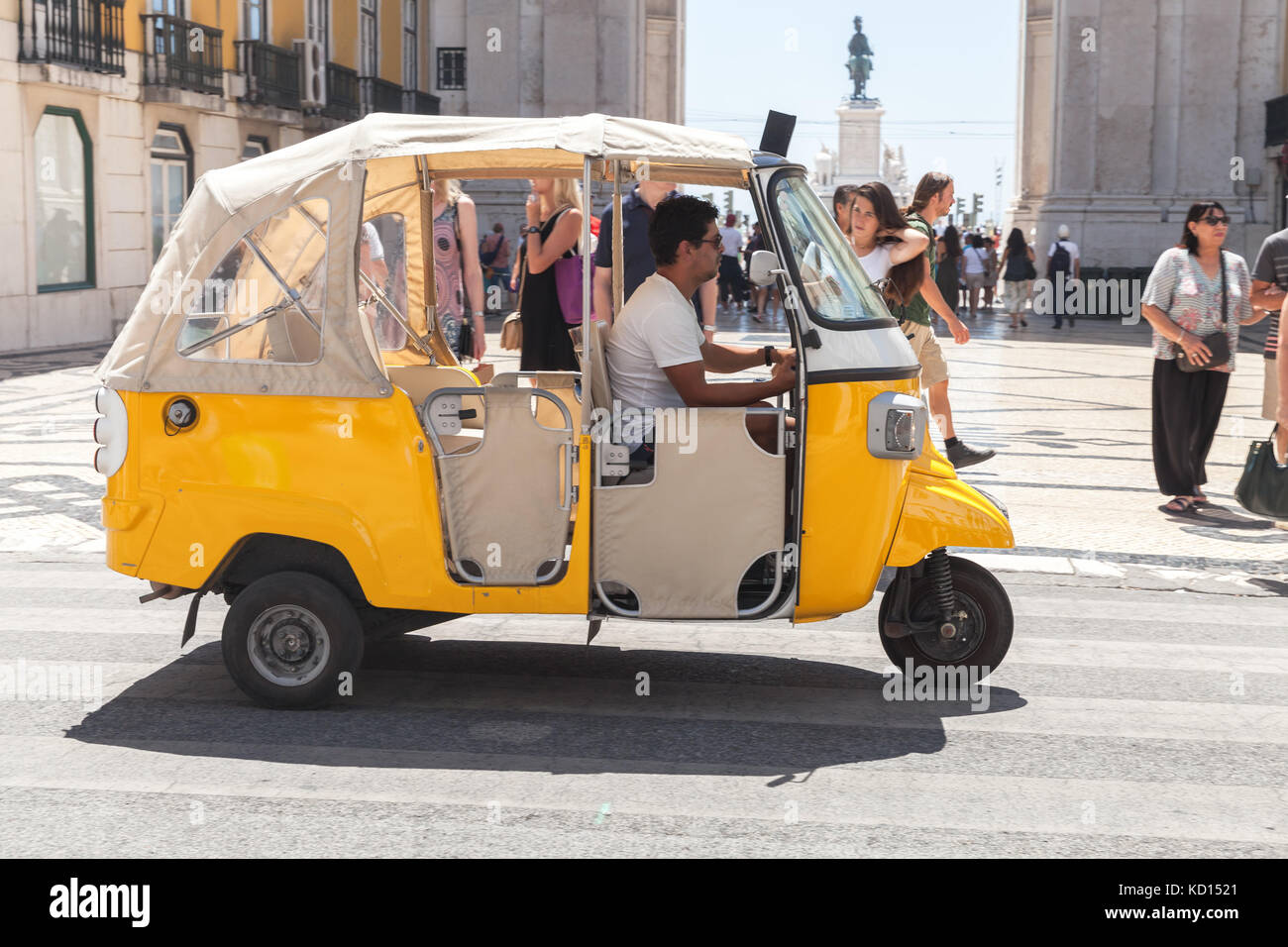 Lisbon, Portugal - August 12, 2017: Yellow Tuk Tuk taxi cab with driver rides the street of Lisbon Stock Photo