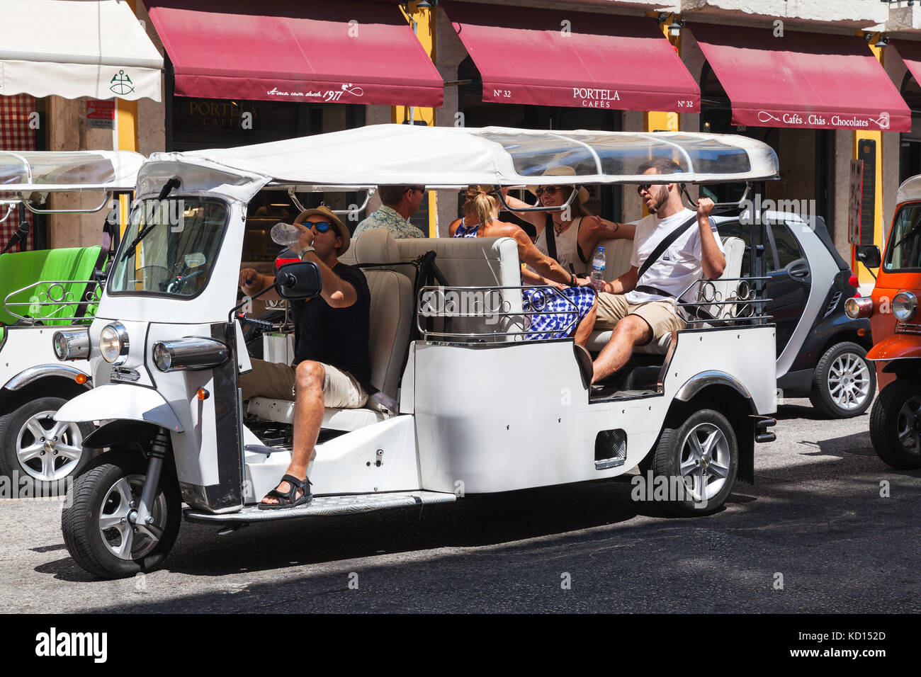 Lisbon, Portugal - August 12, 2017: White Tuk Tuk taxi cab rides the street of Lisbon with tourists as a passengers Stock Photo