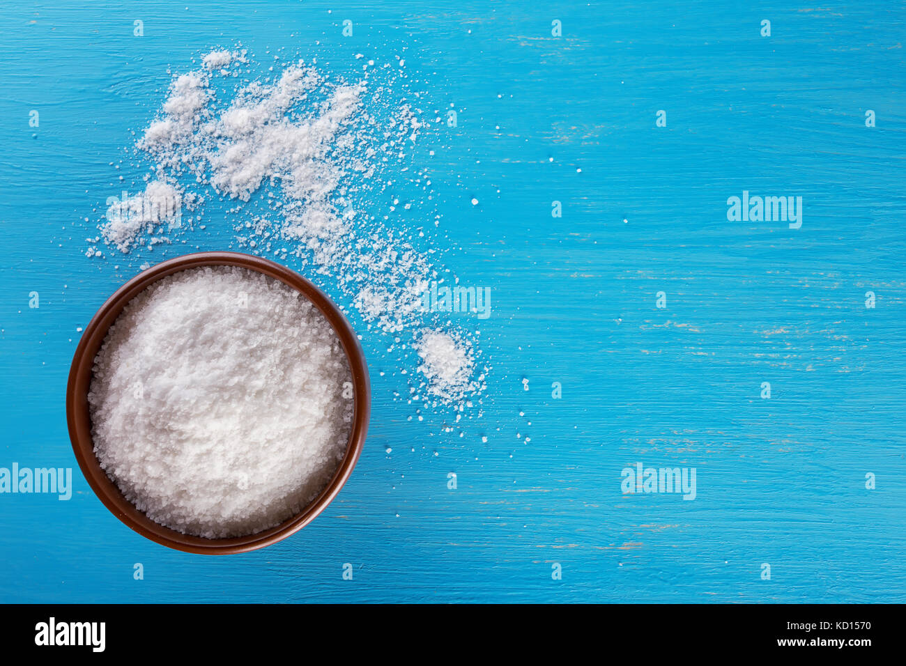 Clay brown bowl with salt on blue background Stock Photo