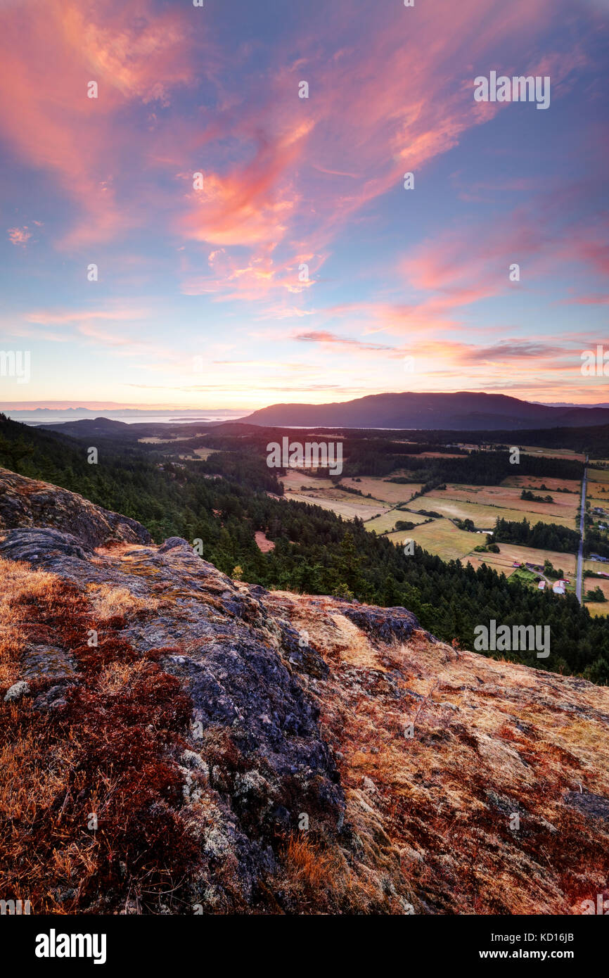 The sun rises over the Mount Constitution and the Crow Valley, viewed from Ship Peak on Turtleback Mountain, Orcas Island, Washington, USA Stock Photo