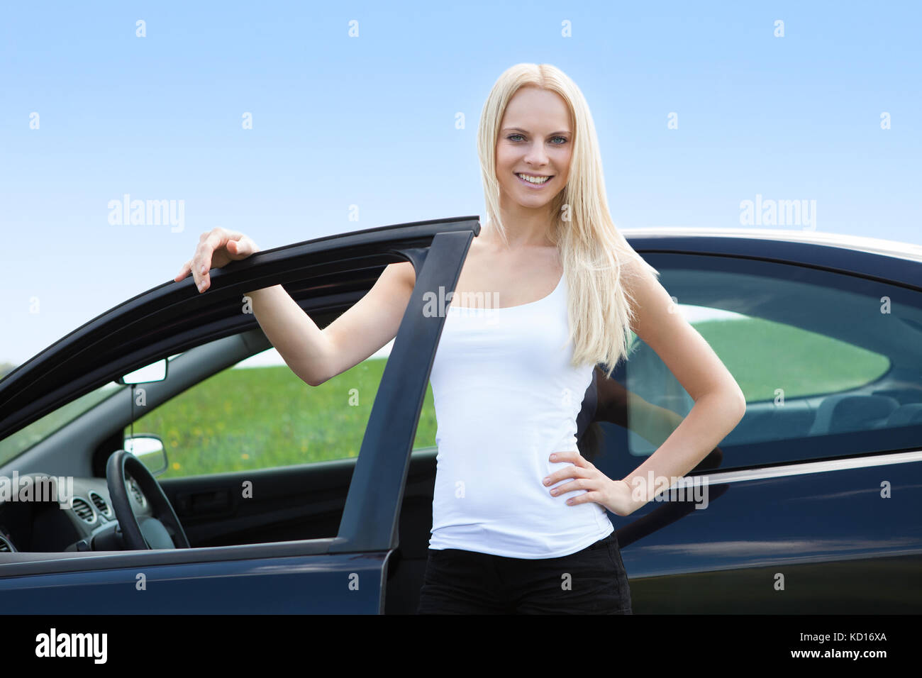 Portrait Of Happy Young Blonde Woman Standing Near Her Car Stock Photo