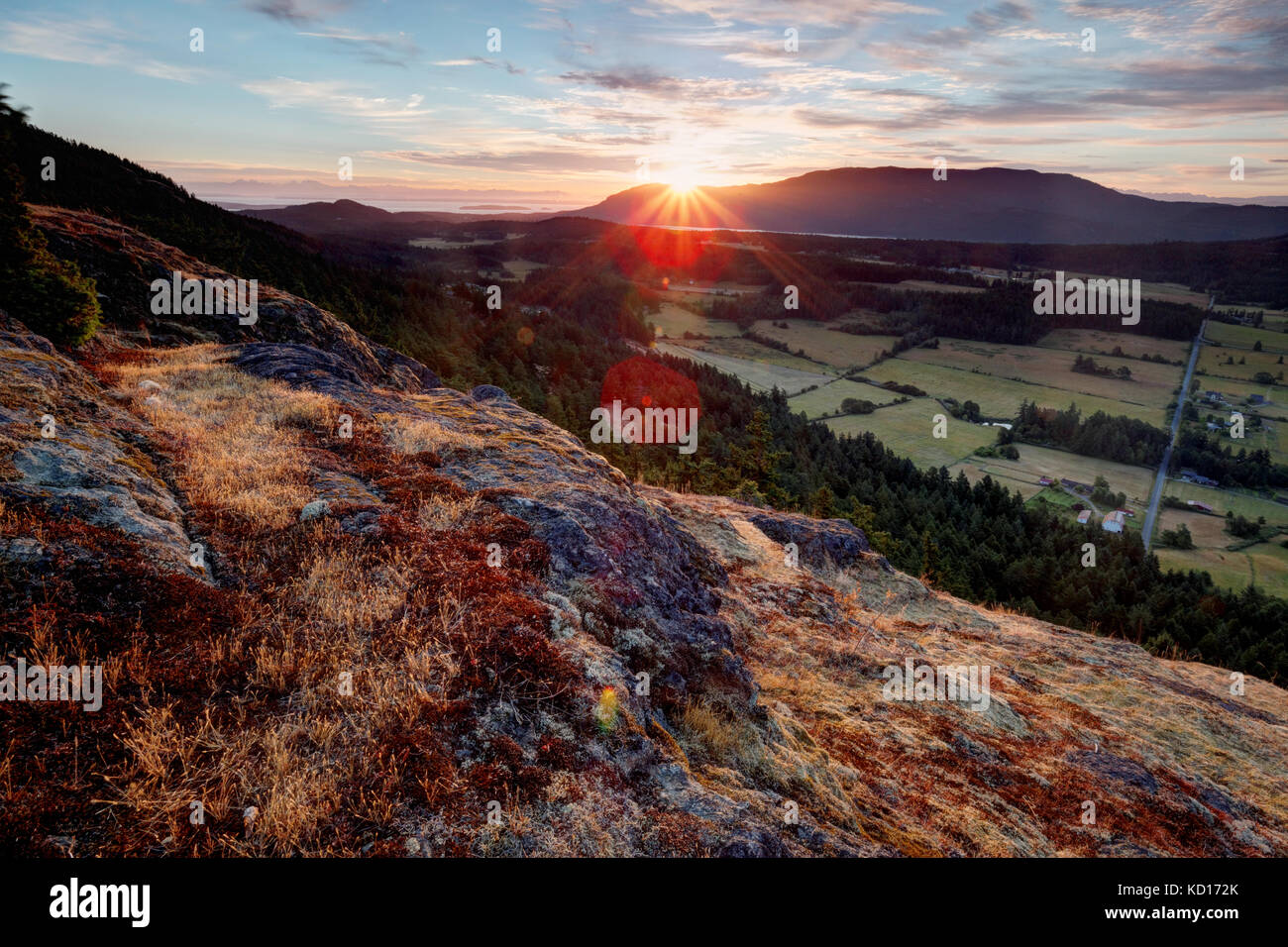 The sun rises over the Mount Constitution and the Crow Valley, viewed from Ship Peak on Turtleback Mountain, Orcas Island, Washington, USA Stock Photo