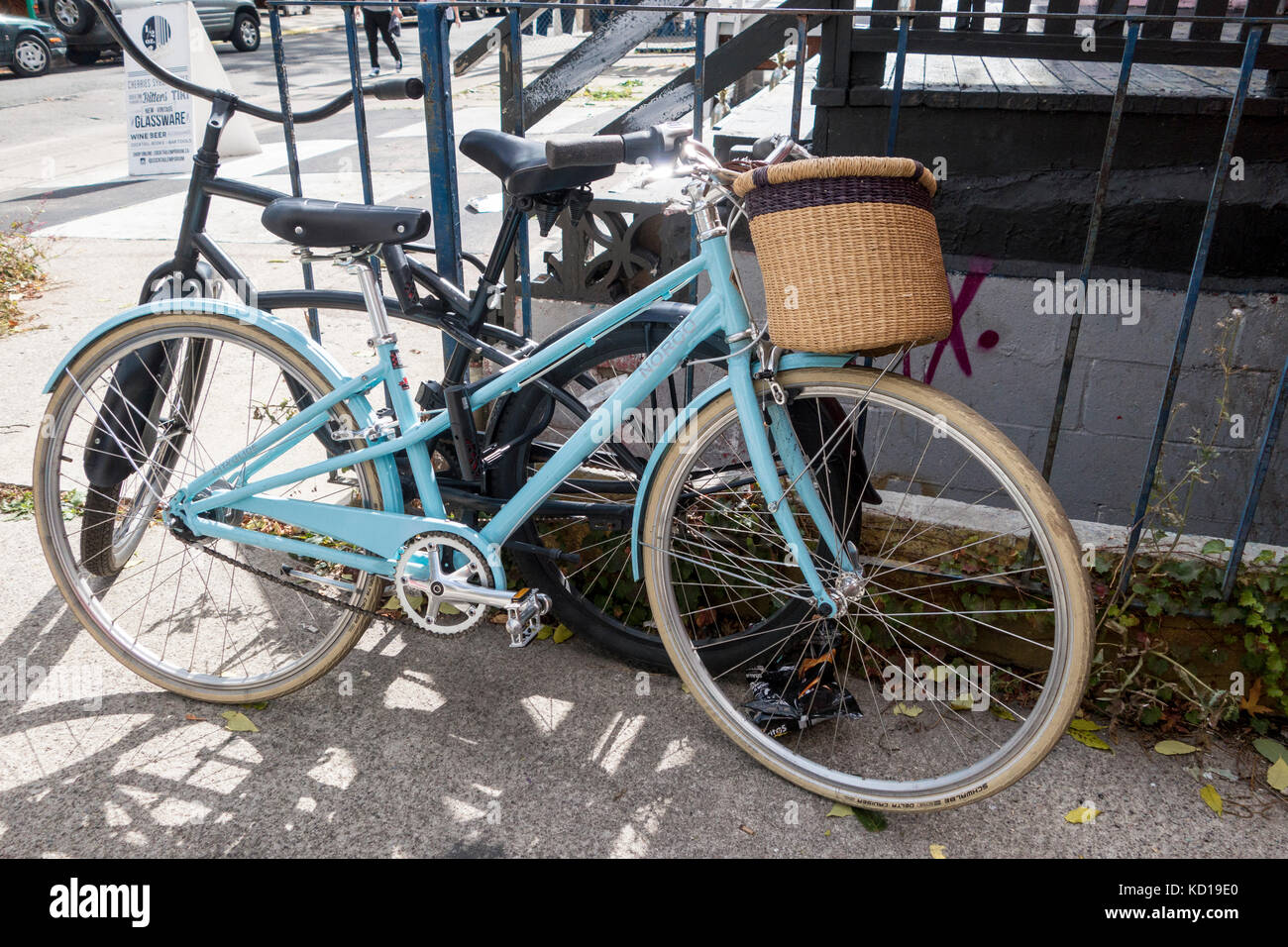 Woman's bicycle with basket locked to fence and another bicycle in Kensington Market in downtown Toronto Ontario Canada Stock Photo