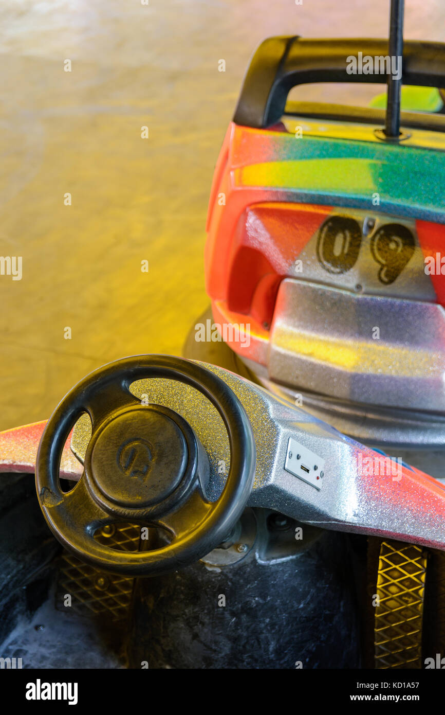 Close-up view of the cockpit of a colorful dodgem car, with steering wheel, pedal and coin slot in a funfair. Stock Photo