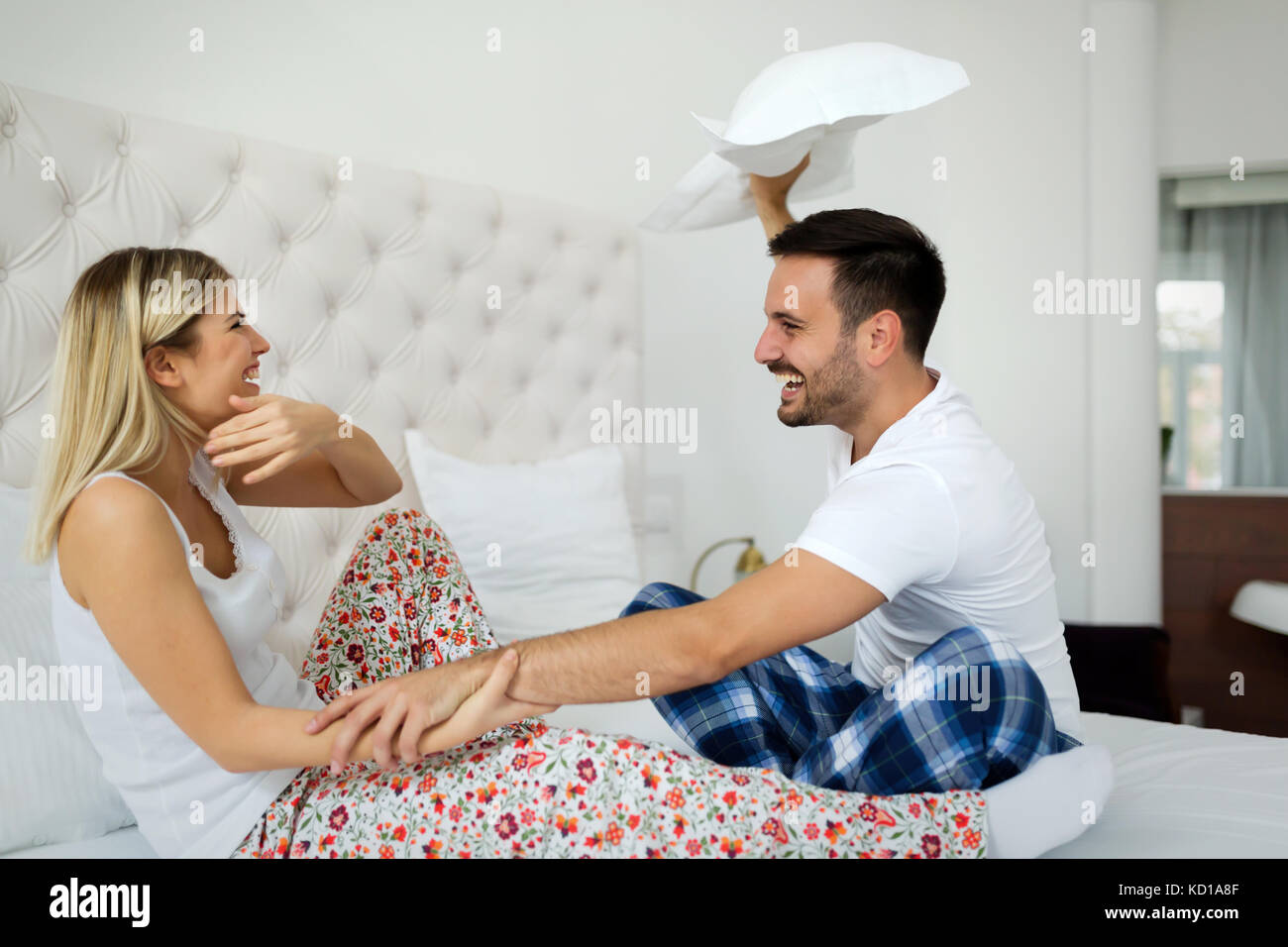 Happy attractive couple play fighting with pillows Stock Photo Alamy