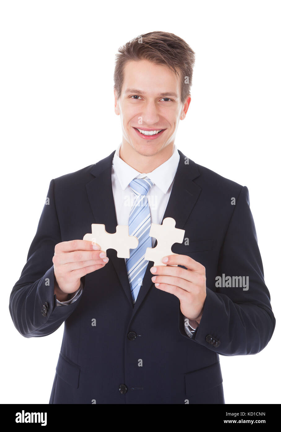Young Businessman Holding Jigsaw Puzzle Over White Background Stock Photo