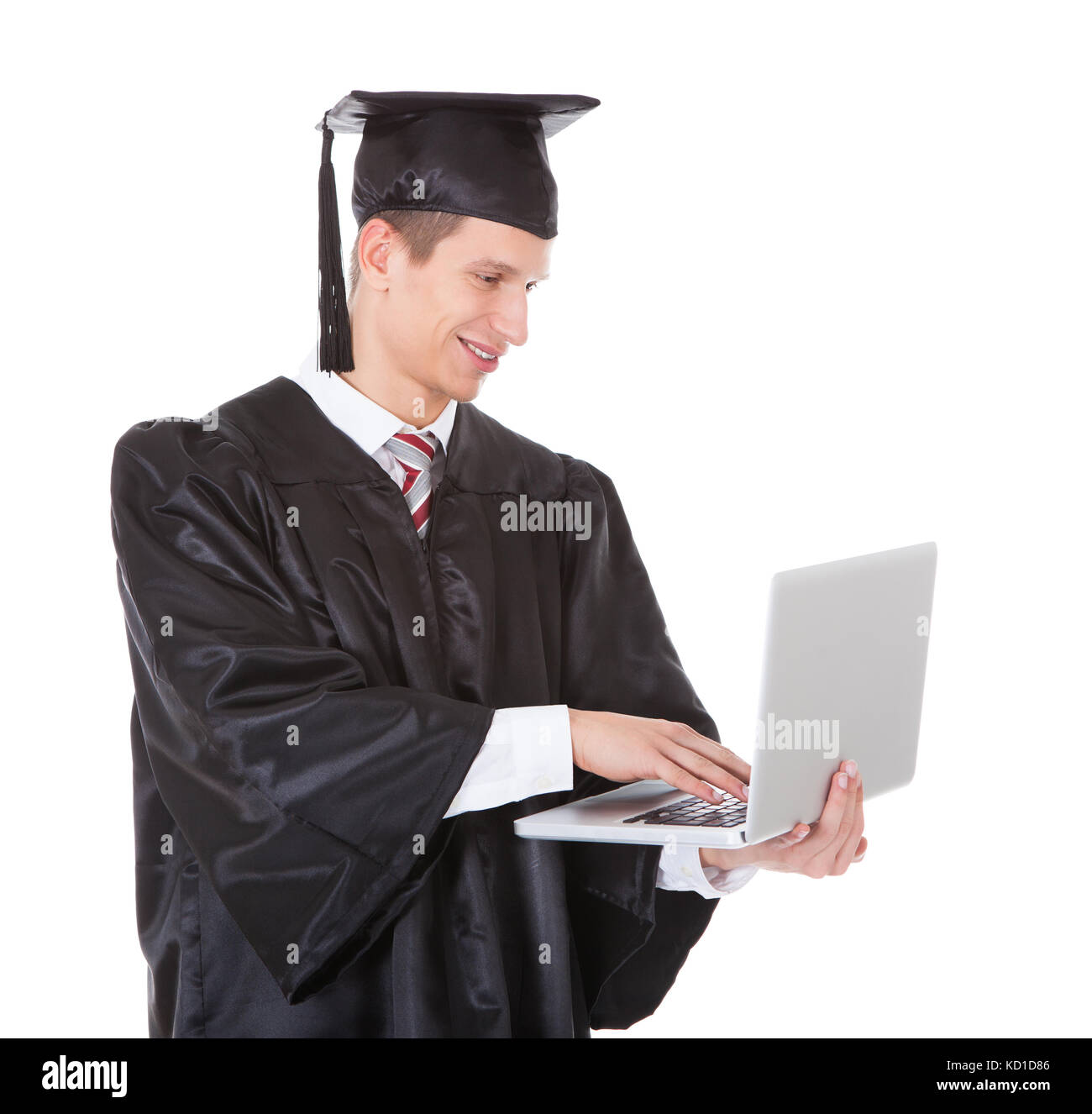 Young Graduate Man Using Laptop Over White Background Stock Photo