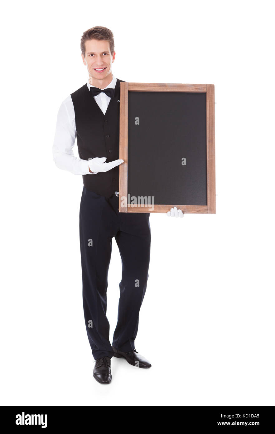 Young Male Waiter Holding Chalkboard Over White Background Stock Photo