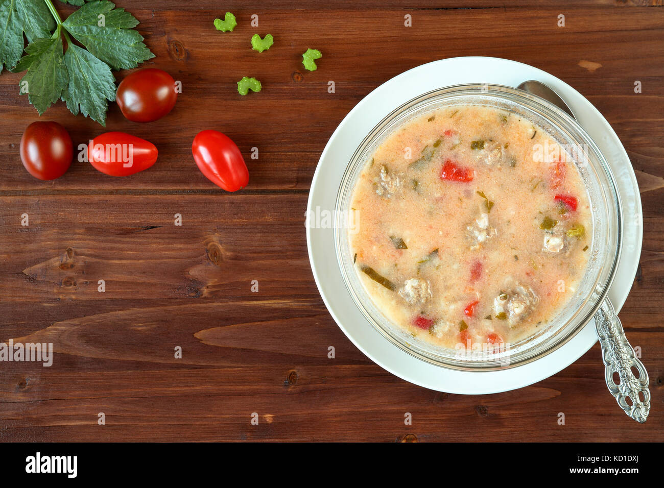 Top view of a delicious homemade meatballs soup with tomatoes, celery and rice on a wooden table. Traditional bulgarian cuisine (Supa Topcheta) Stock Photo