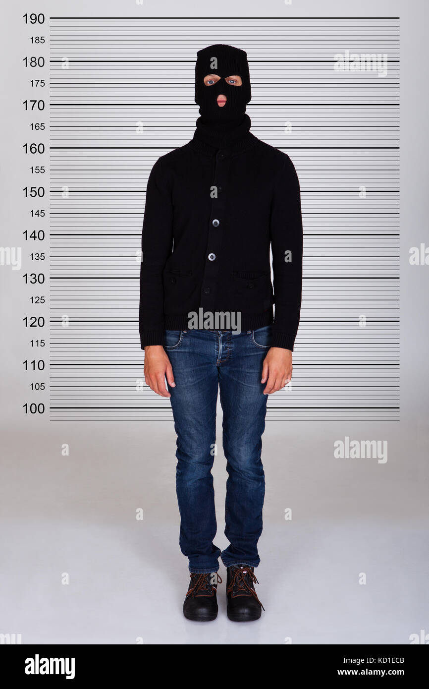 Burglar Wearing Balaclava Standing Against Police Lineup Stock Photo